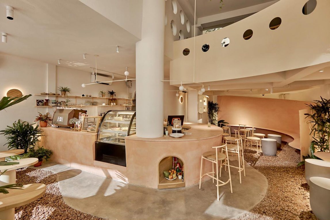 An indoor café space designed to feel open and airy, with greenery and bar seating that invites interaction.