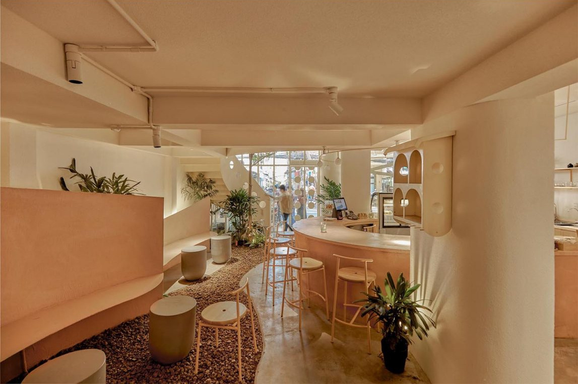 An indoor café space designed to feel open and airy, with greenery and bar seating that invites interaction.