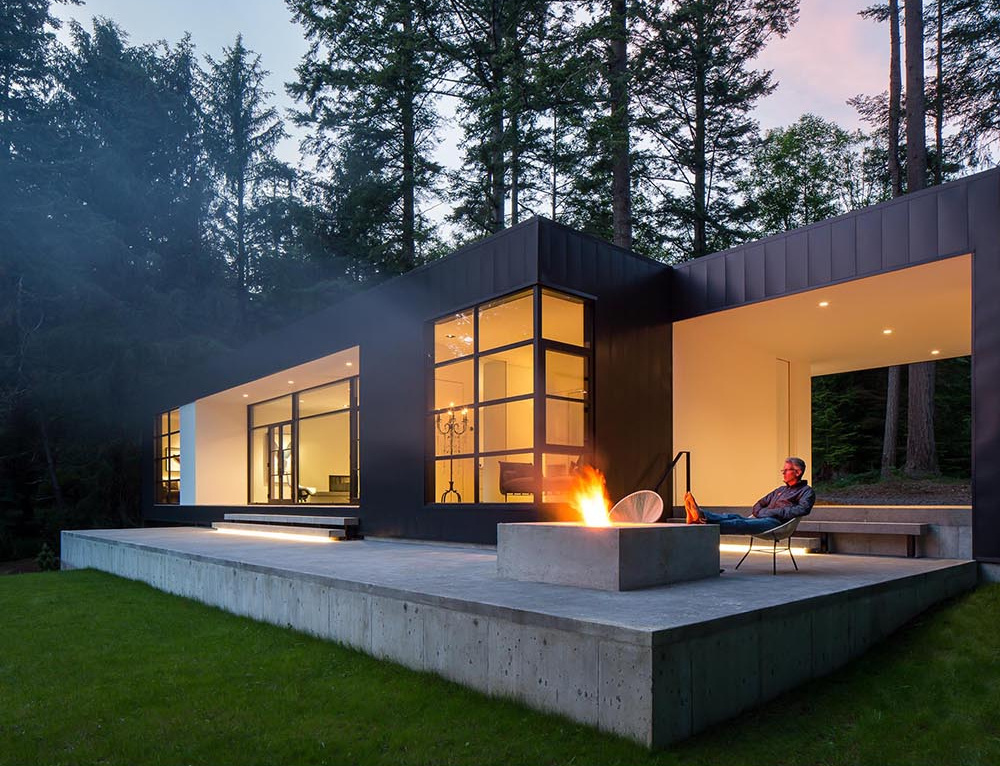 Black metal and white stucco create a striking modern exterior for this Orcas Island home, set against forest views.