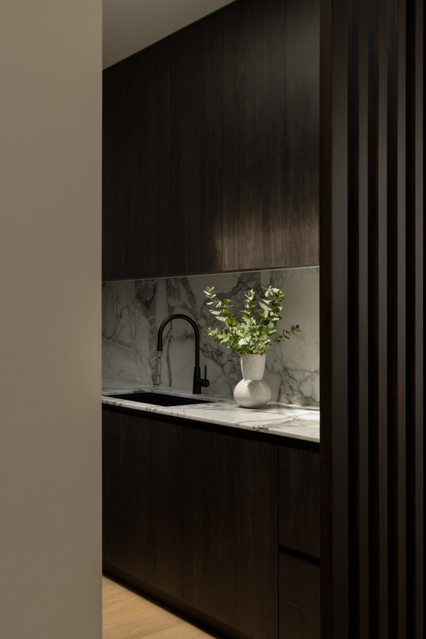 This kitchen, with its dark cabinets and rounded island, plays a central role in the home’s layout, designed to handle everything from daily meals to larger family events.