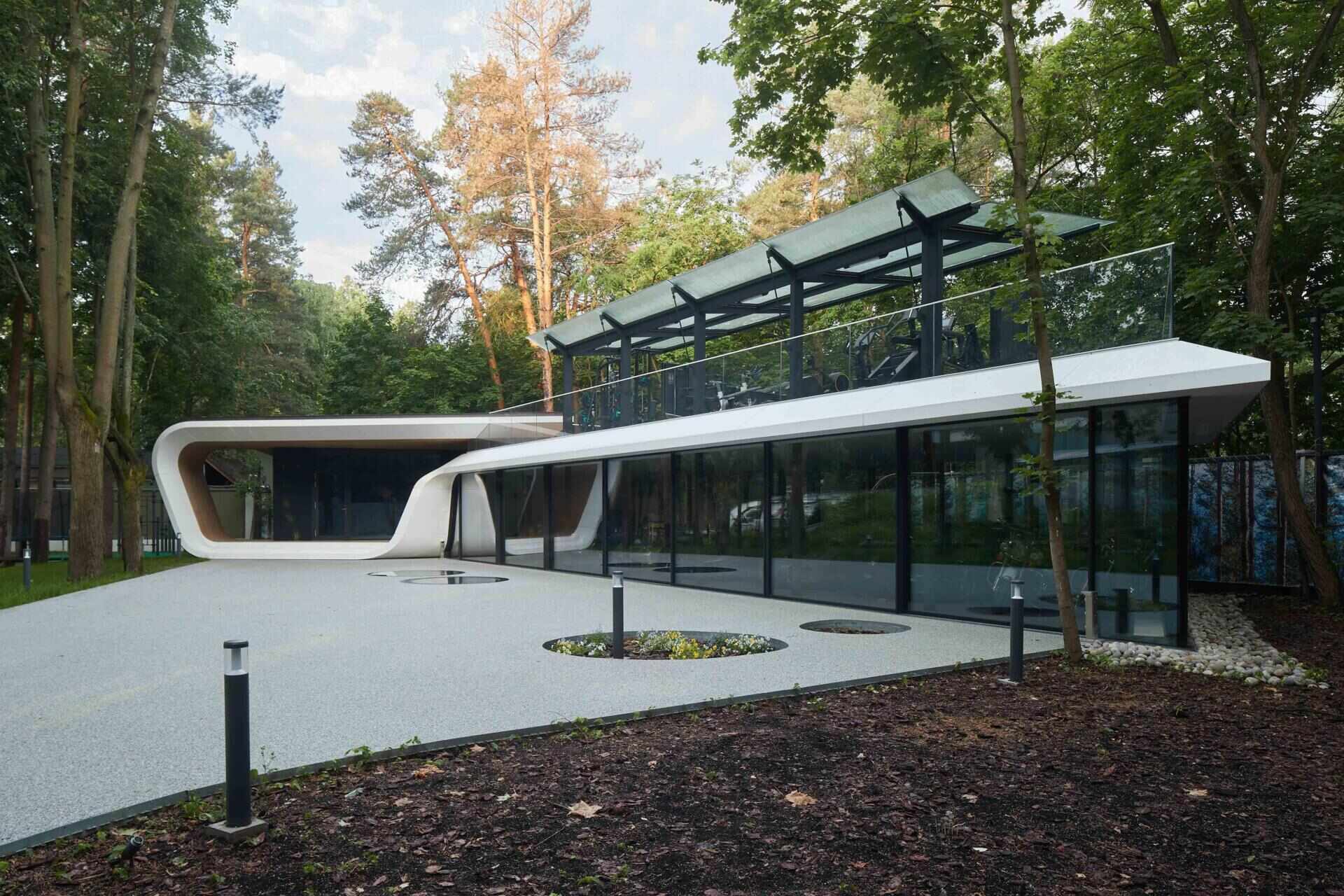 A modern garage by ATRIUM expands a private estate, turning car storage into a striking architectural feature in a forest setting.