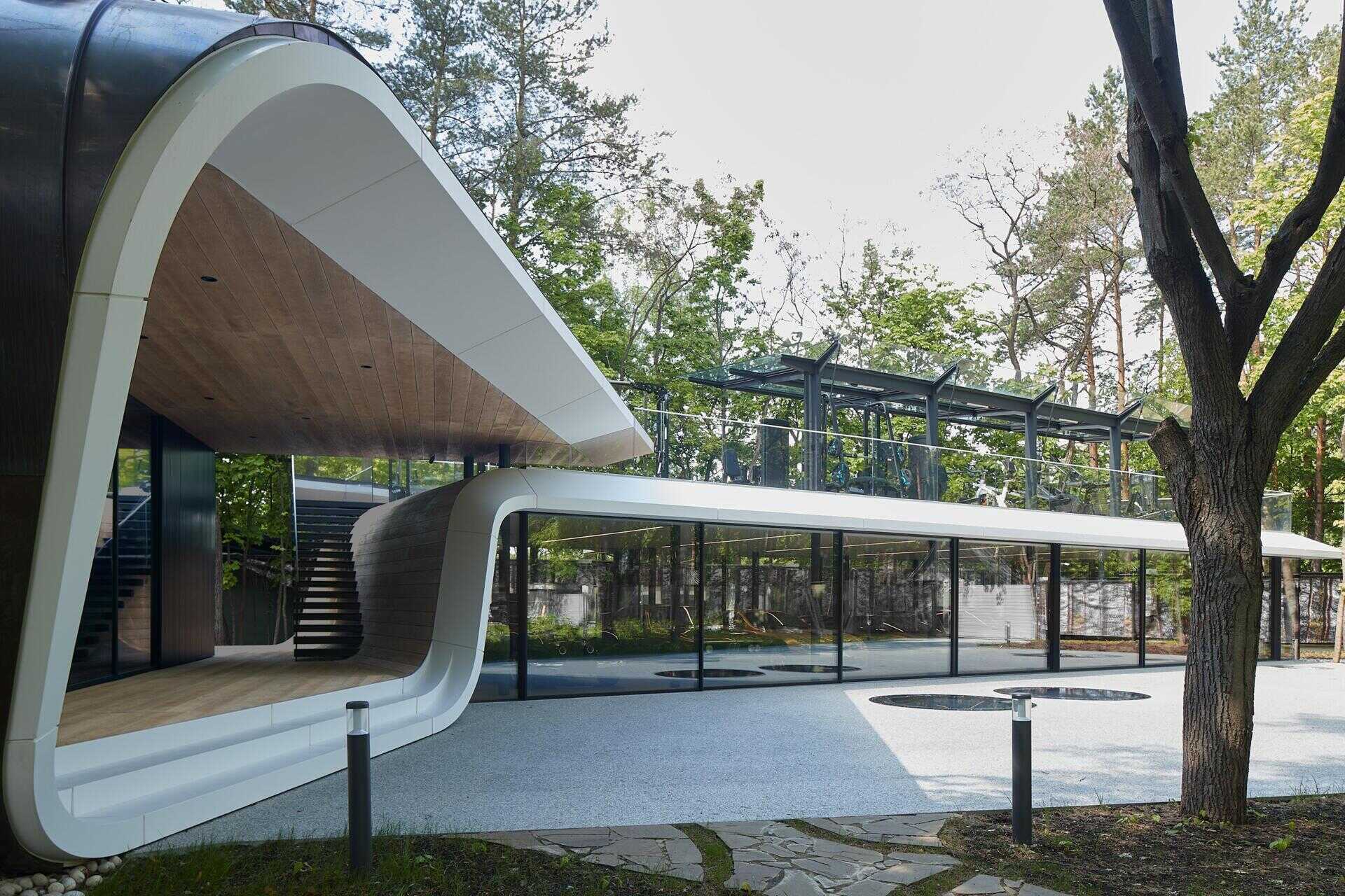 A modern garage by ATRIUM expands a private estate, turning car storage into a striking architectural feature in a forest setting.