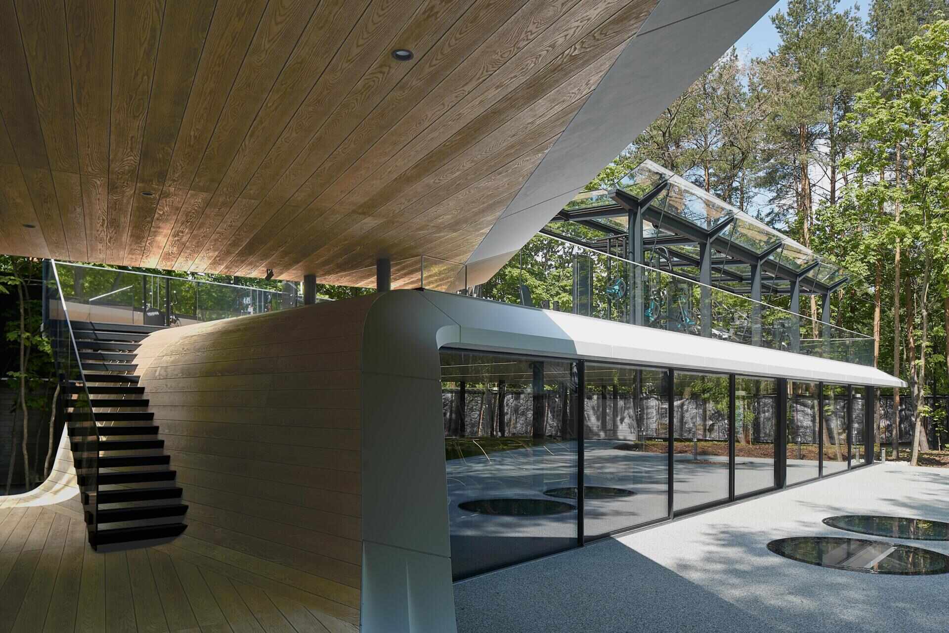 A modern garage by ATRIUM expands a private estate, turning car storage into a striking architectural feature in a forest setting.