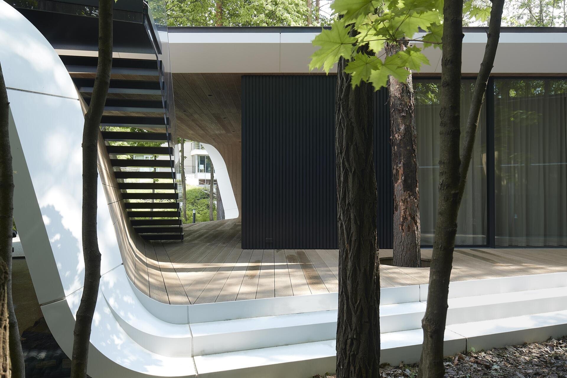 A modern garage by ATRIUM expands a private estate, turning car storage into a striking architectural feature in a forest setting.
