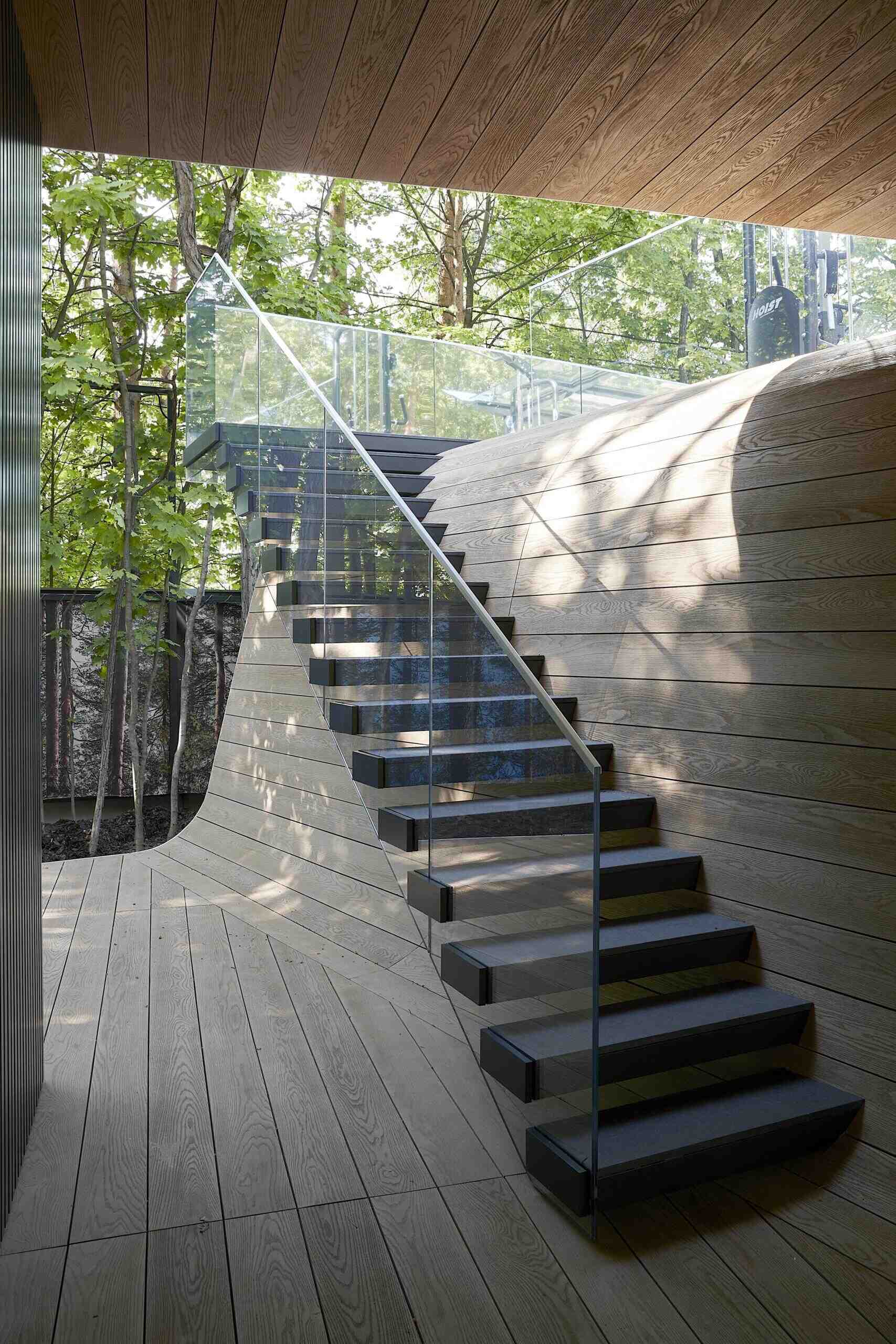 A modern garage by ATRIUM expands a private estate, turning car storage into a striking architectural feature in a forest setting.