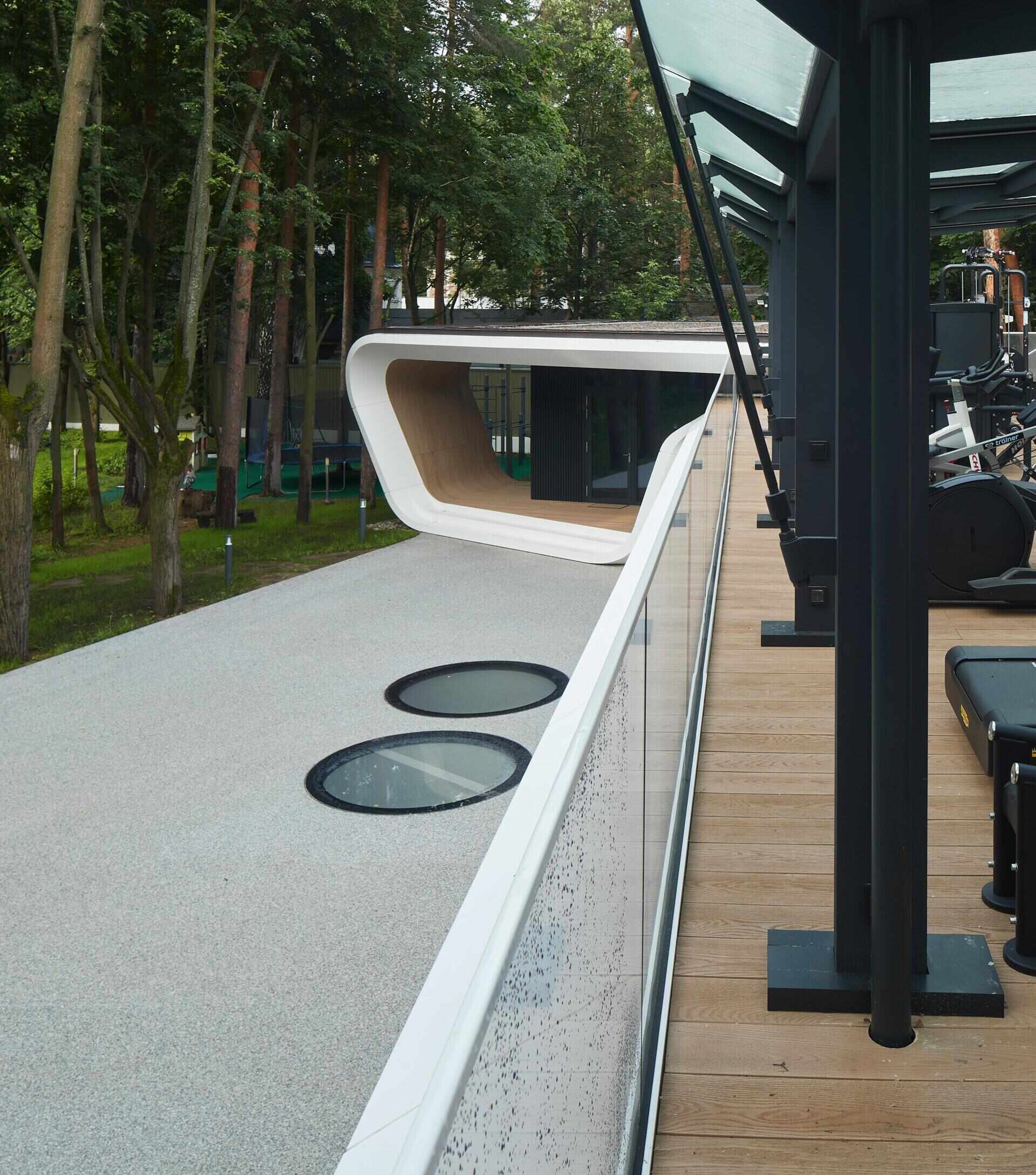 A modern garage by ATRIUM expands a private estate, turning car storage into a striking architectural feature in a forest setting.