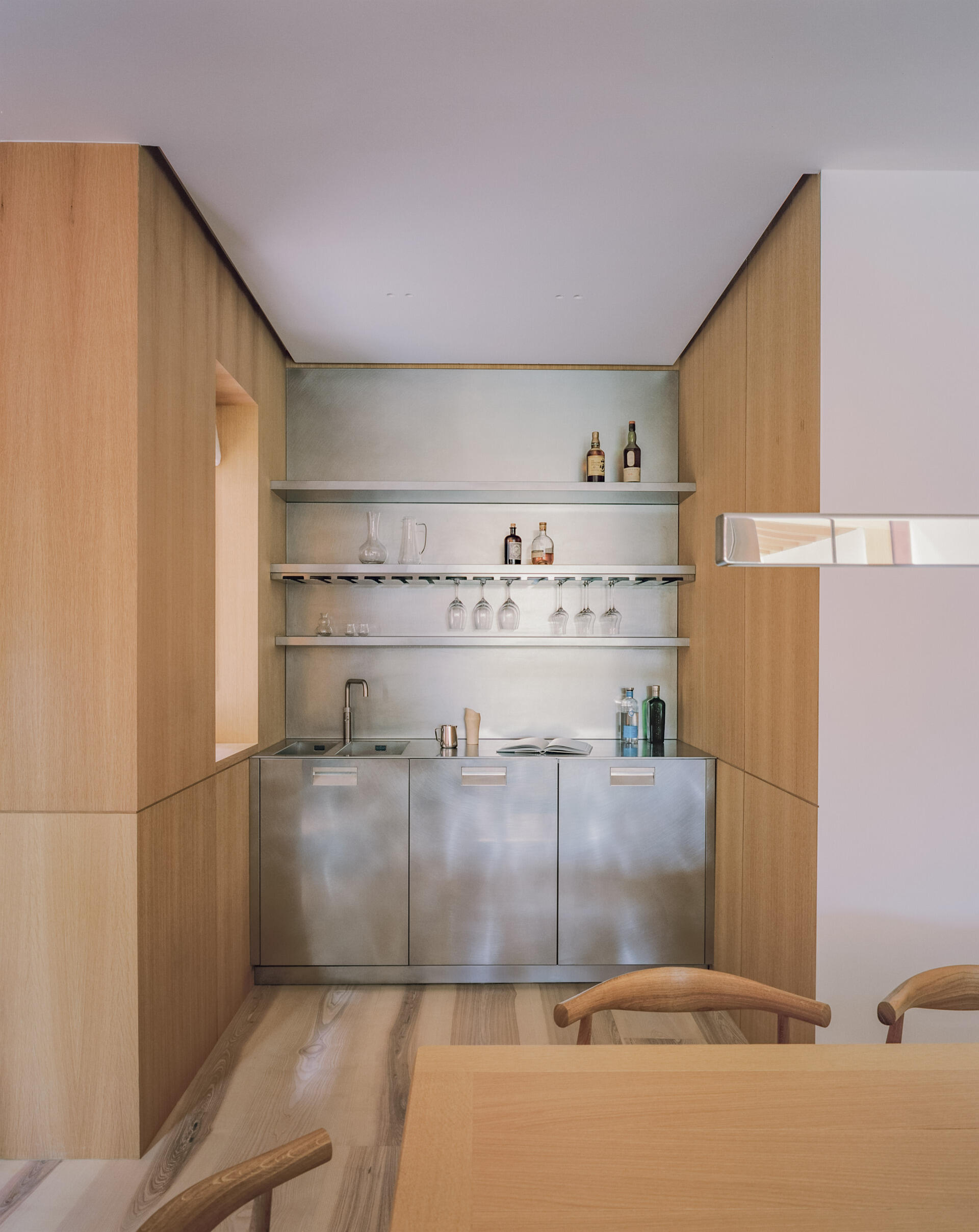 A dining space with a fireplace and built-in bar creates a warm, social hub within the open plan layout.