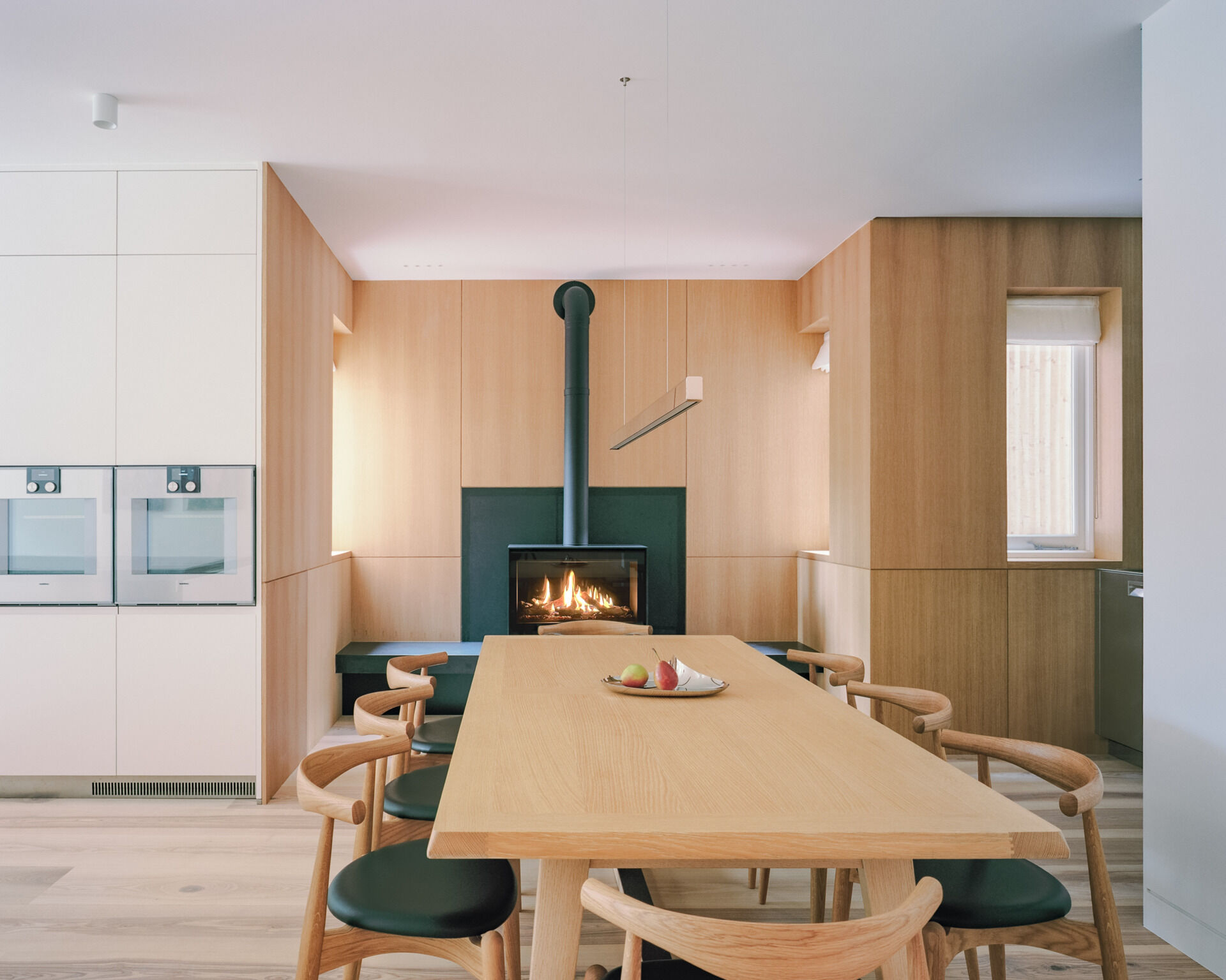 A dining space with a fireplace and built-in bar creates a warm, social hub within the open plan layout.