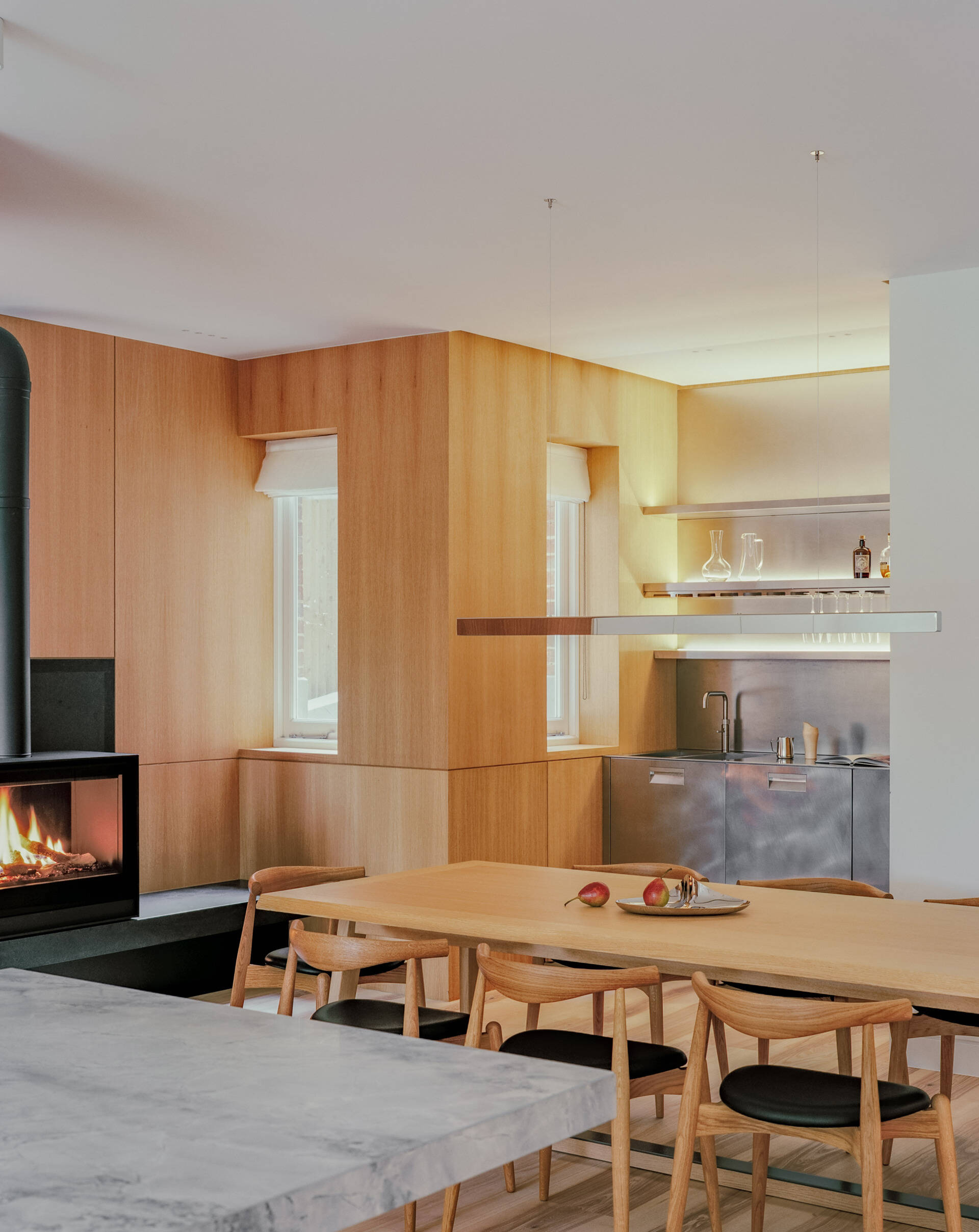 A dining space with a fireplace and built-in bar creates a warm, social hub within the open plan layout.