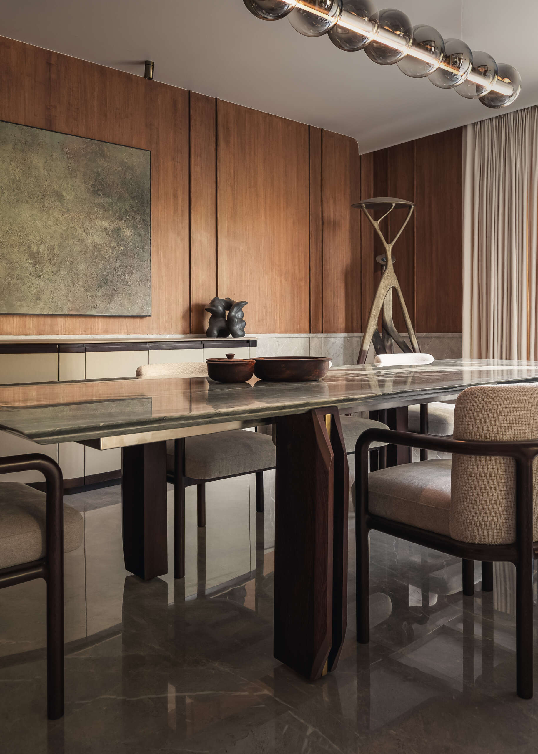 The dining space sits comfortably within the overall flow of the home. It doesn’t try to stand apart, instead working with the same soft tones and material palette seen throughout. A large 10-seater table with lighting overhead draws attention, while the sideboard blends into its surrounds.