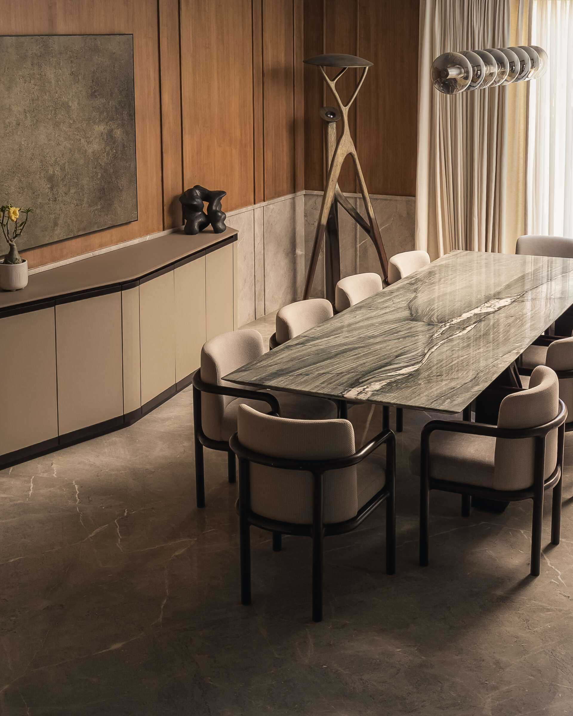 The dining space sits comfortably within the overall flow of the home. It doesn’t try to stand apart, instead working with the same soft tones and material palette seen throughout. A large 10-seater table with lighting overhead draws attention, while the sideboard blends into its surrounds.