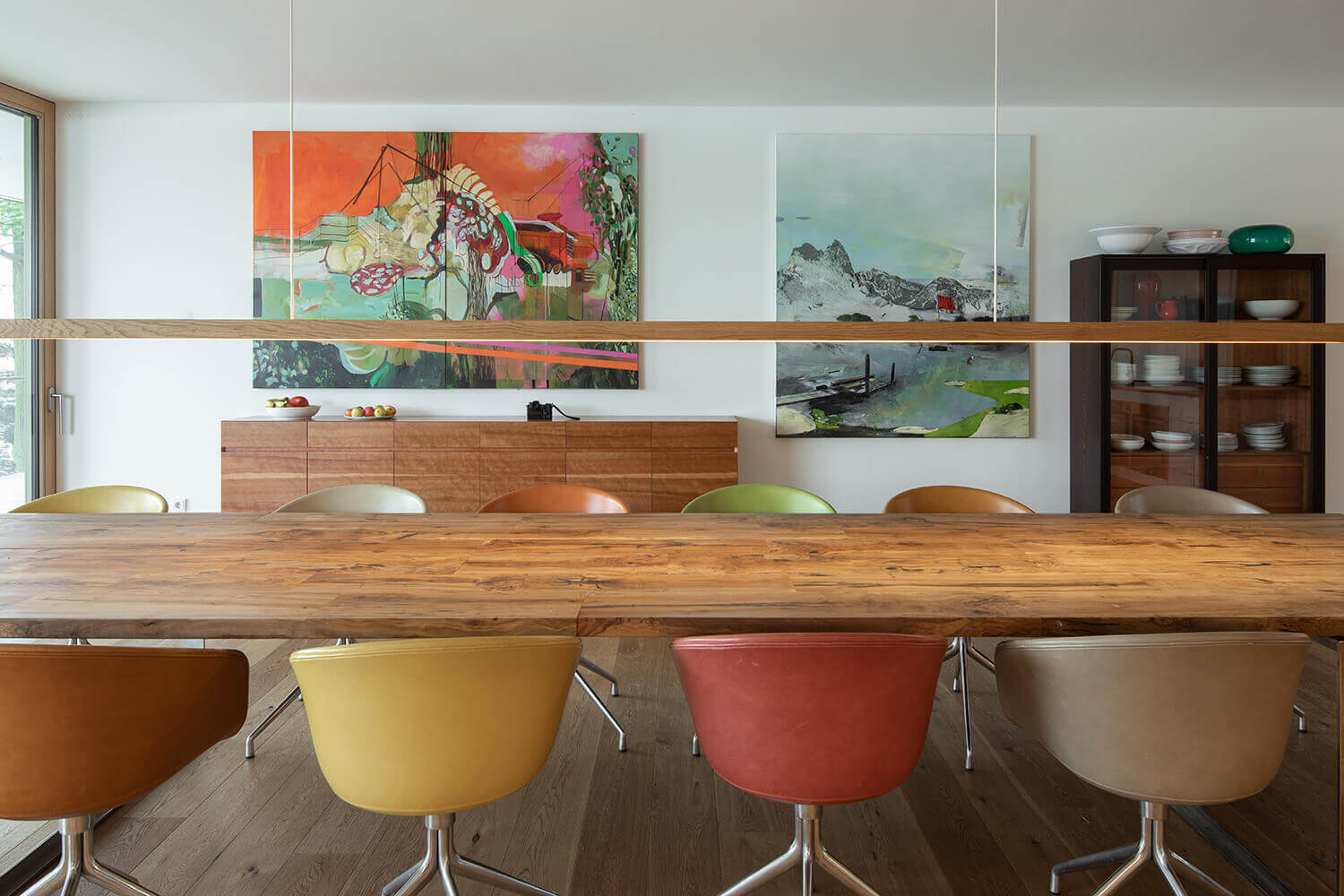 An extra-long dining table and clean white cabinetry define this modern space, with sliding doors opening to the outdoors.