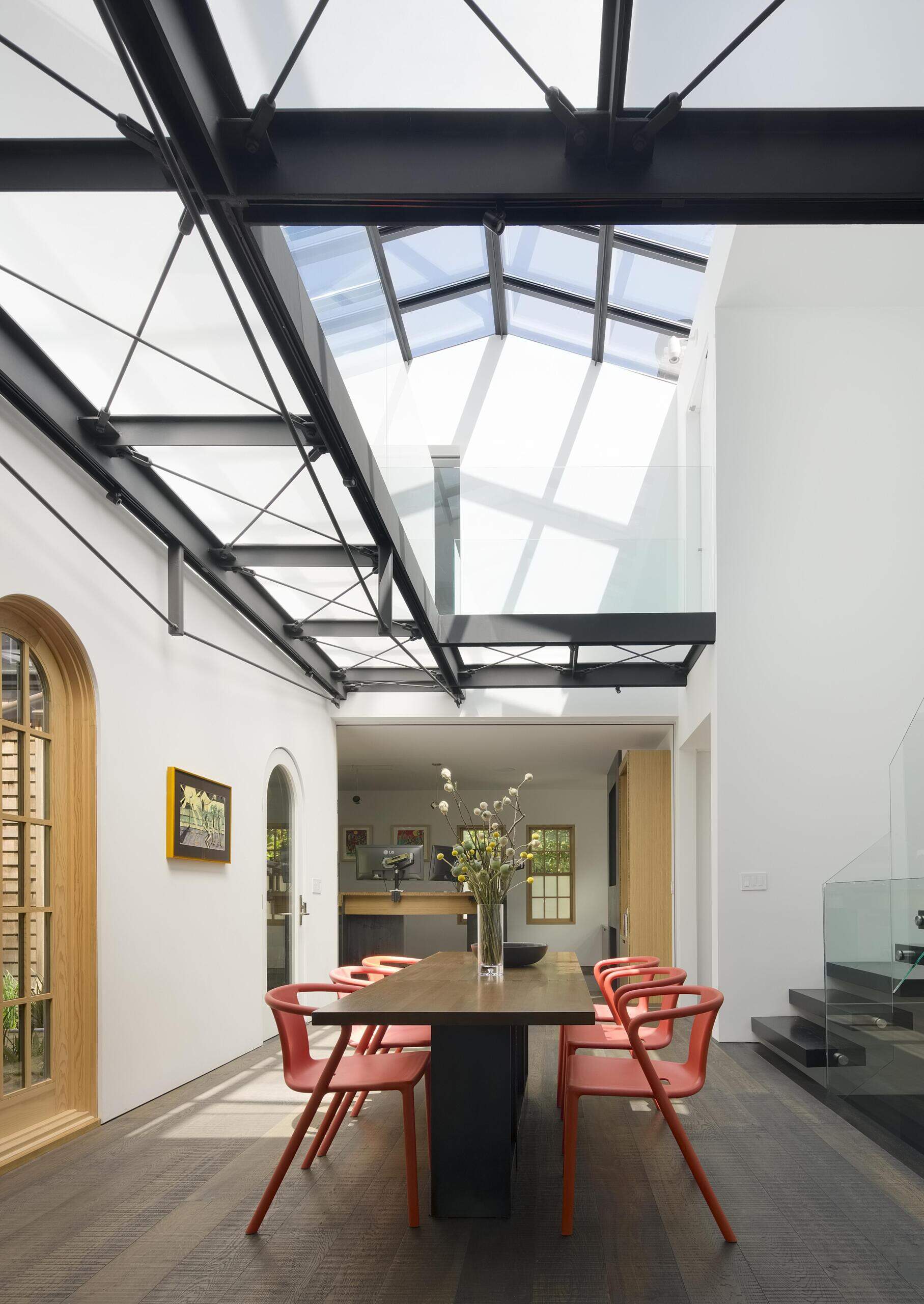 A dramatic double-height dining atrium transforms a historic home with natural light and a custom folding walnut table.