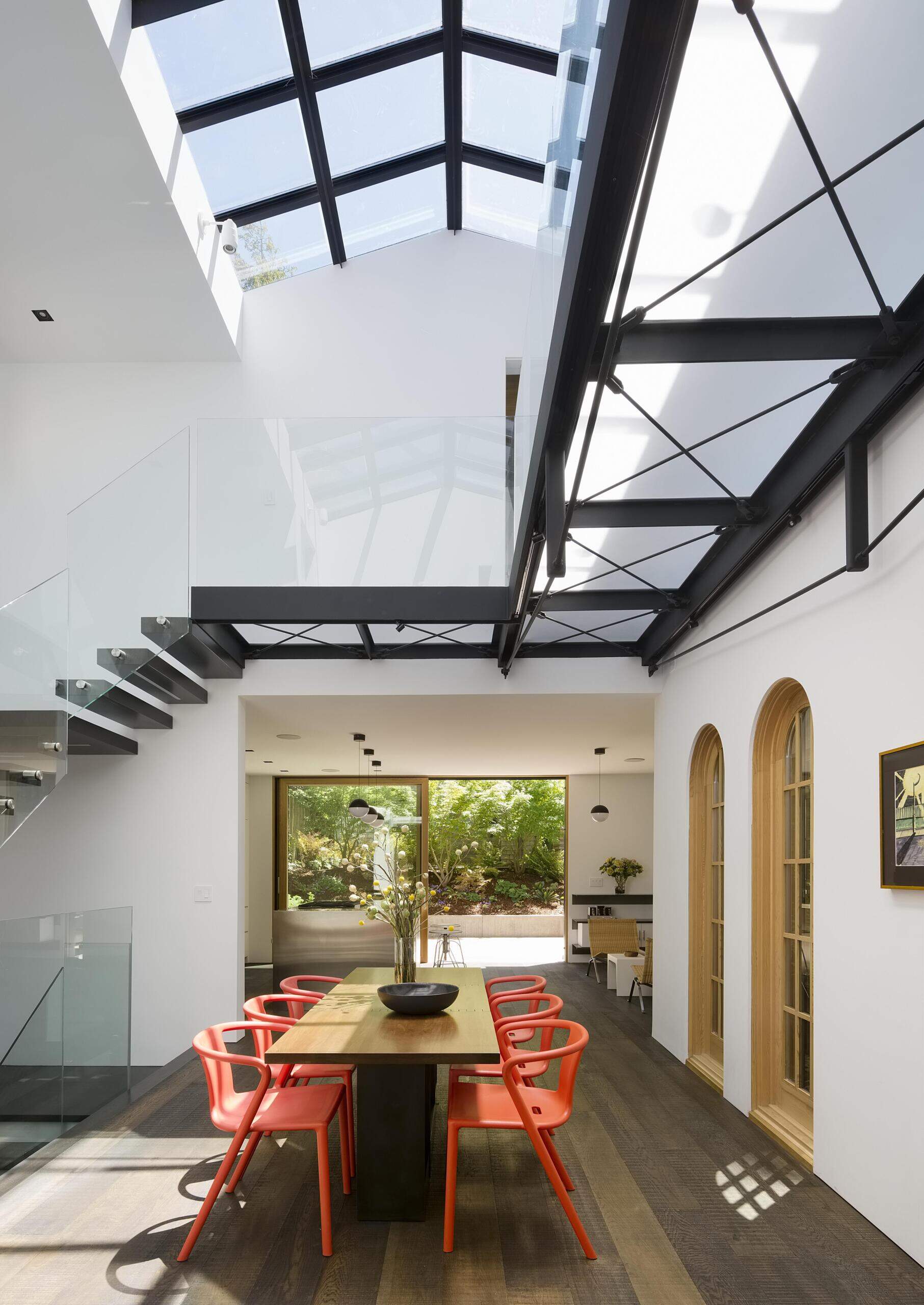 A dramatic double-height dining atrium transforms a historic home with natural light and a custom folding walnut table.