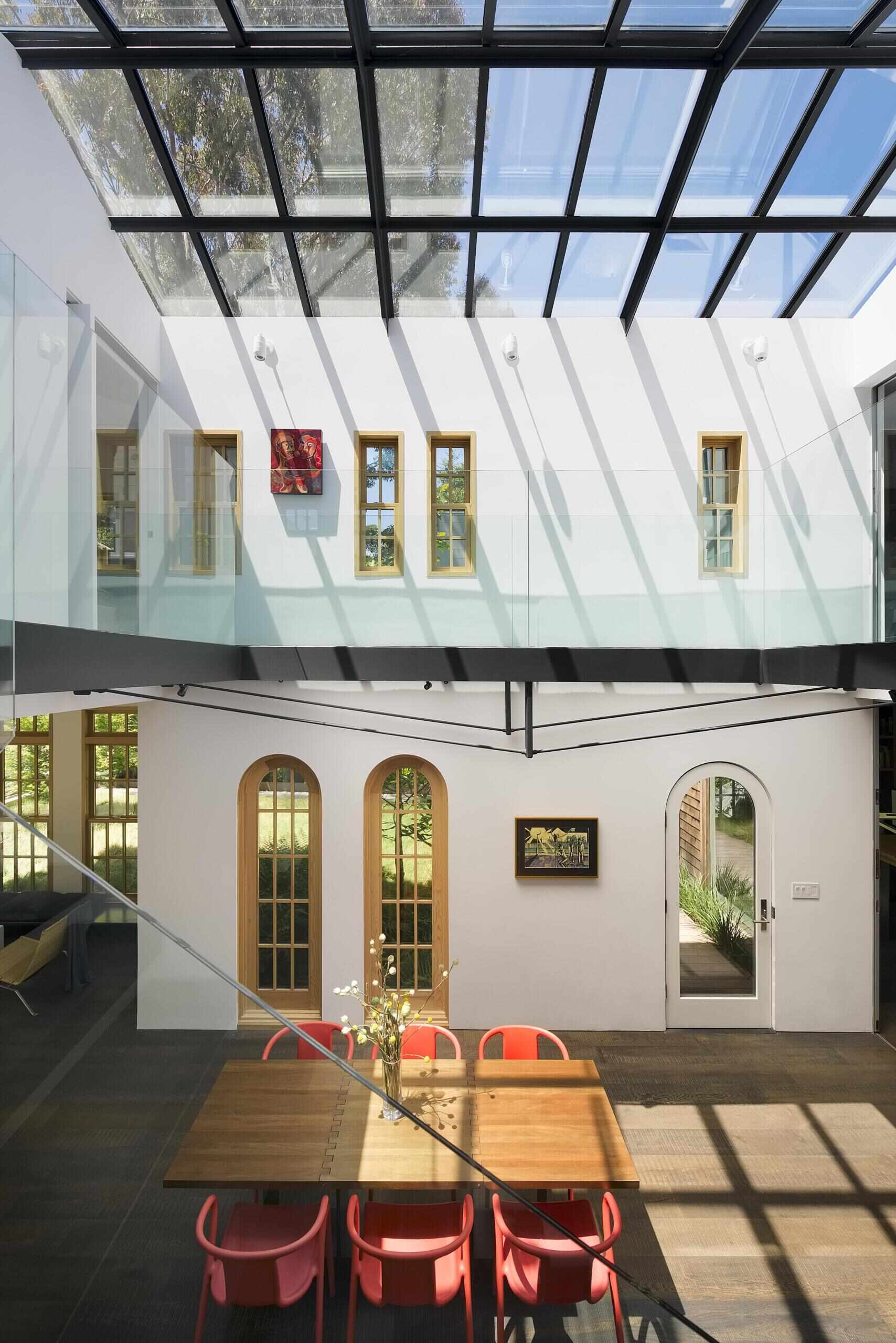 A dramatic double-height dining atrium transforms a historic home with natural light and a custom folding walnut table.