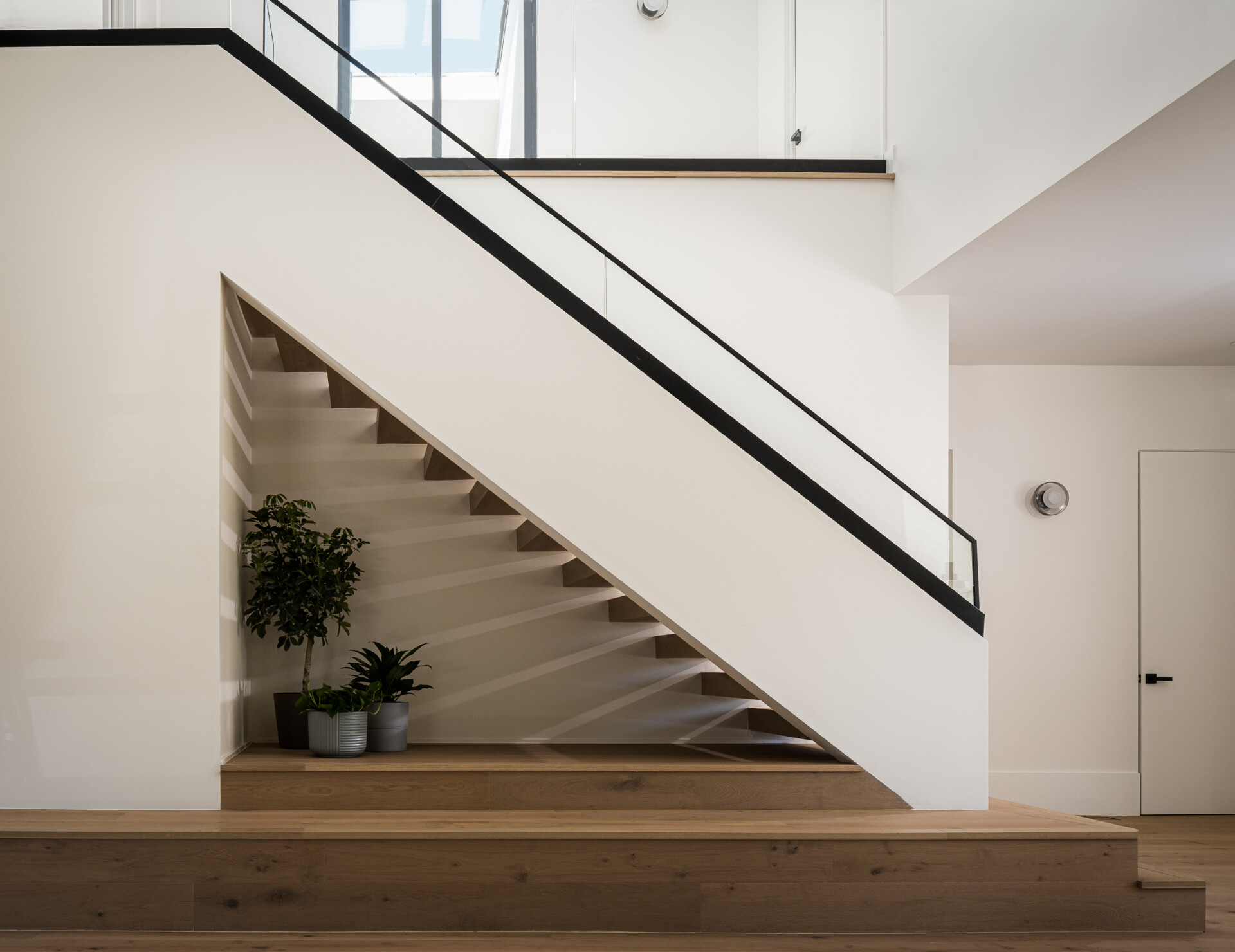 Inside this modern home, the foyer introduces the home’s material palette and spatial clarity. A built-in bench adds function right at the threshold, offering a simple moment of pause before moving deeper inside.