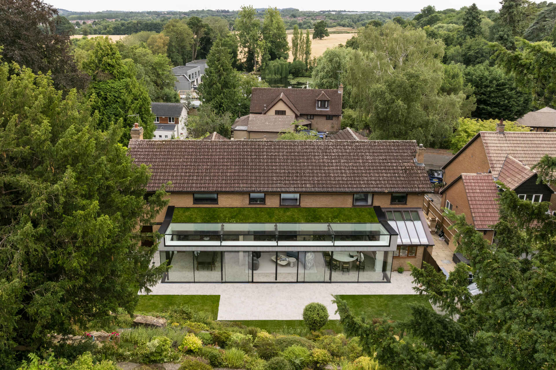 This rear extension with a green roof, uses full-height glazing to connect the kitchen and living areas directly to a sloping garden, creating a seamless indoor-outdoor feel.