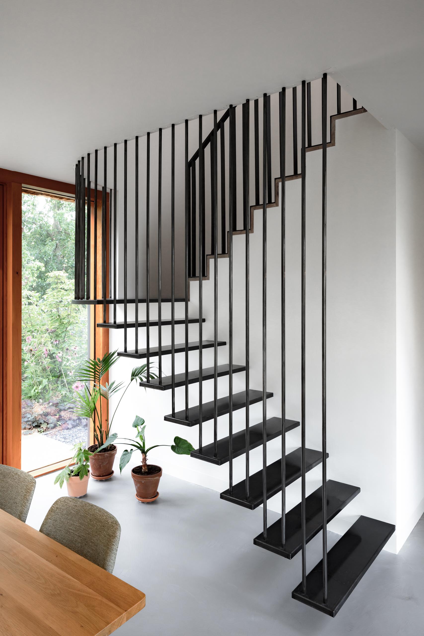Black stairs introduce contrast against the lighter interior, adding depth and definition near the dining area.