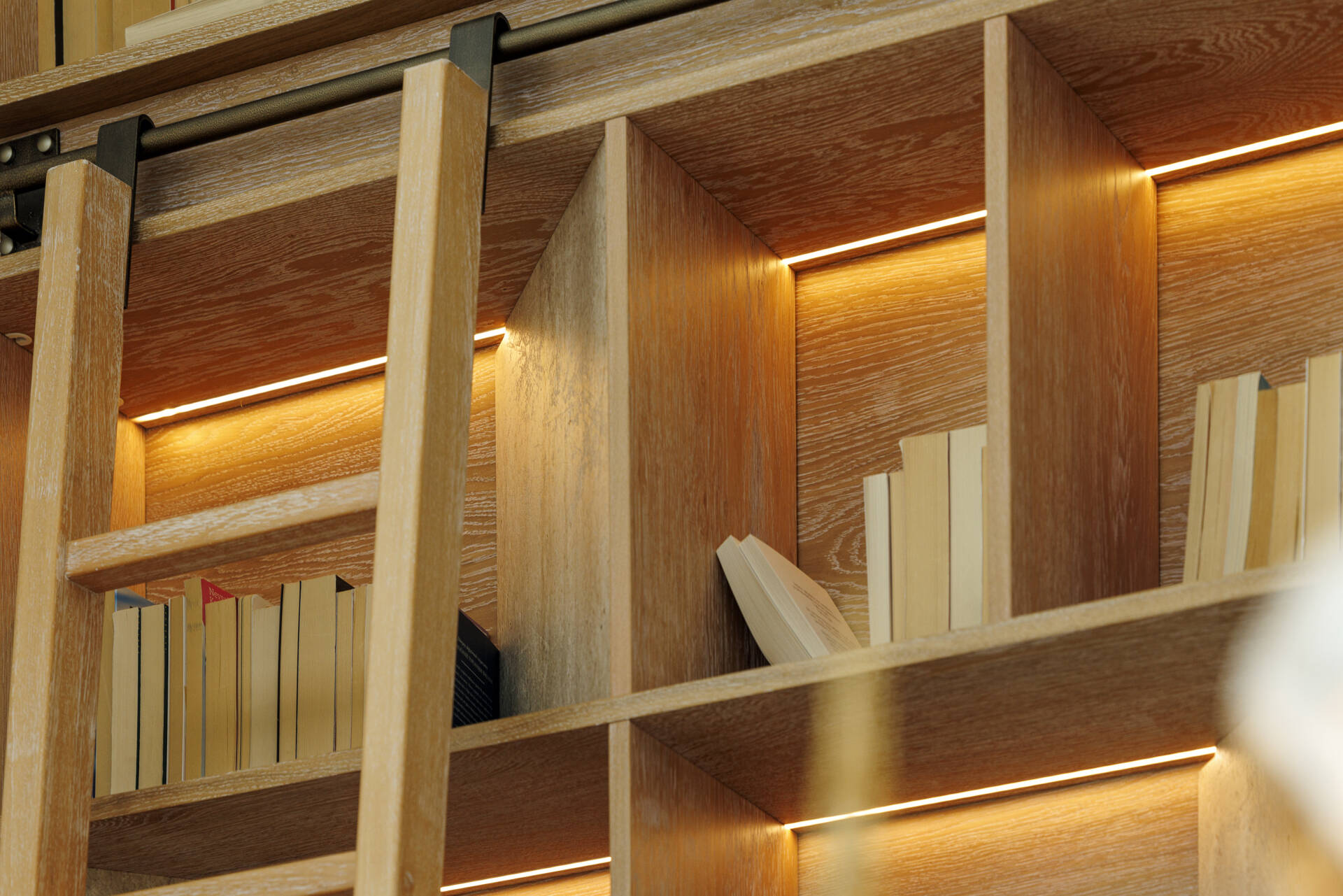 In this loft apartment, a full-height wood library with lighting, becomes a focal point, pointing to knowledge as an ongoing process, something built step by step over time.