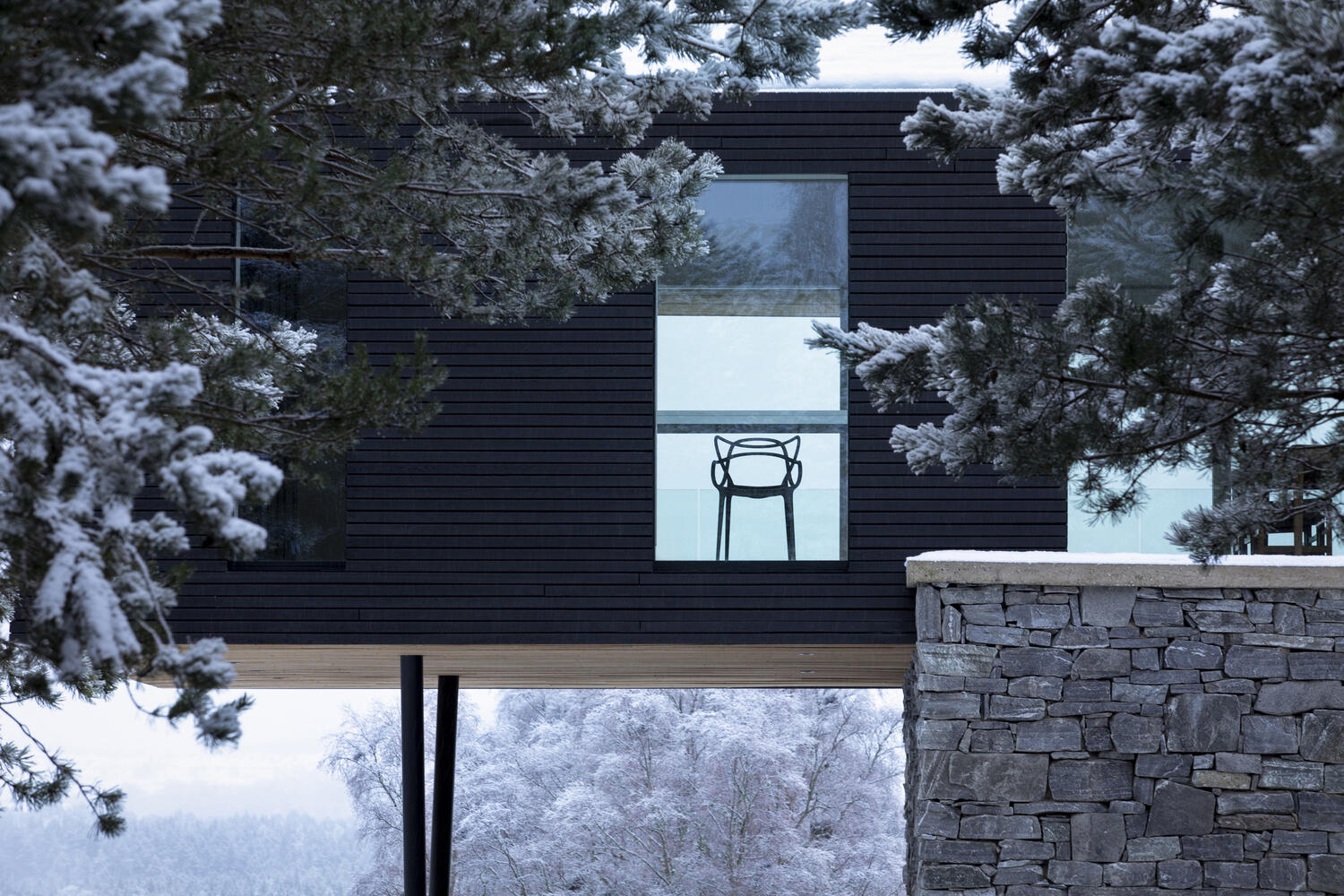 A timber and glass extension sits above a solid stone base, creating a modern contrast that feels both grounded and open to the landscape.