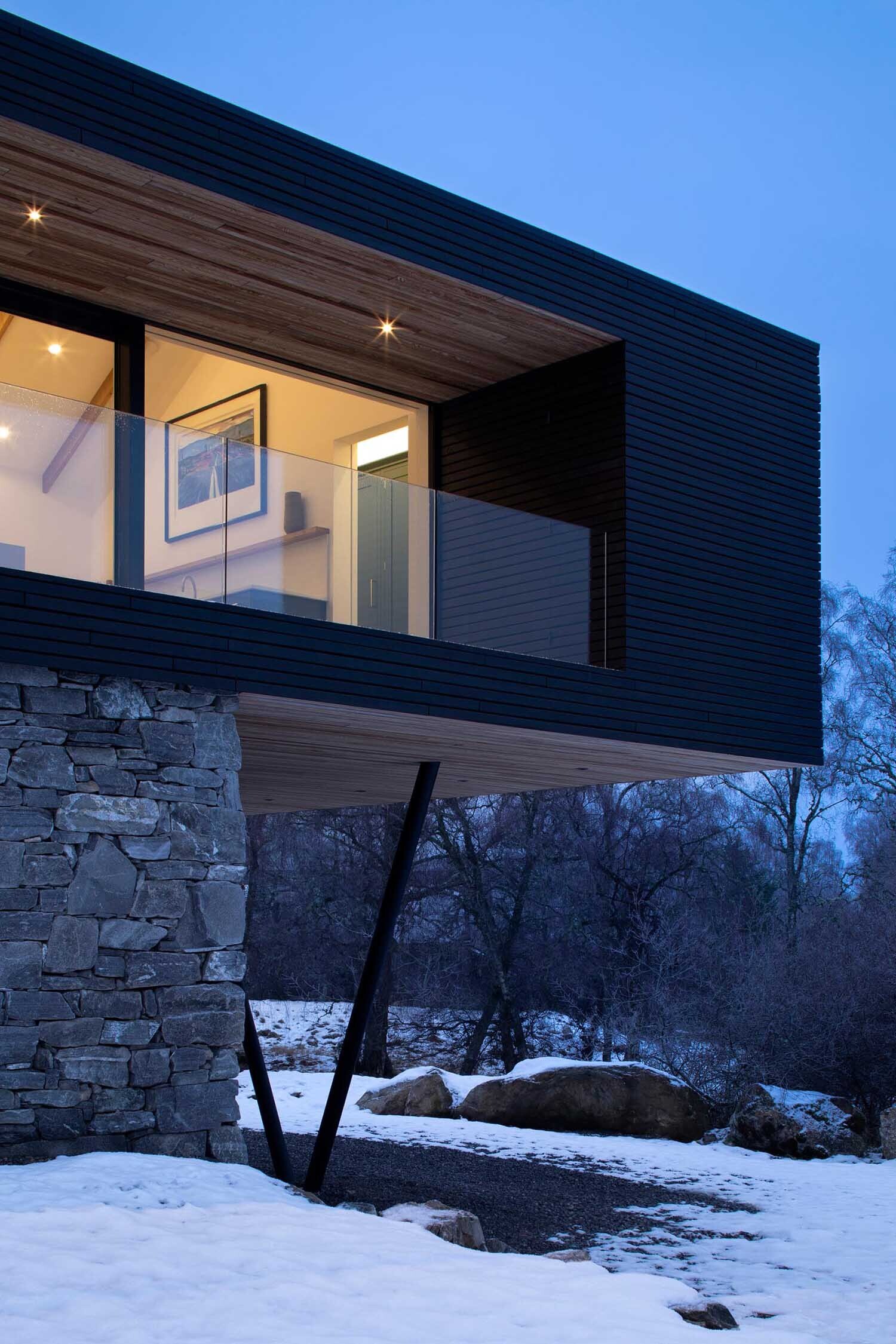 A timber and glass extension sits above a solid stone base, creating a modern contrast that feels both grounded and open to the landscape.