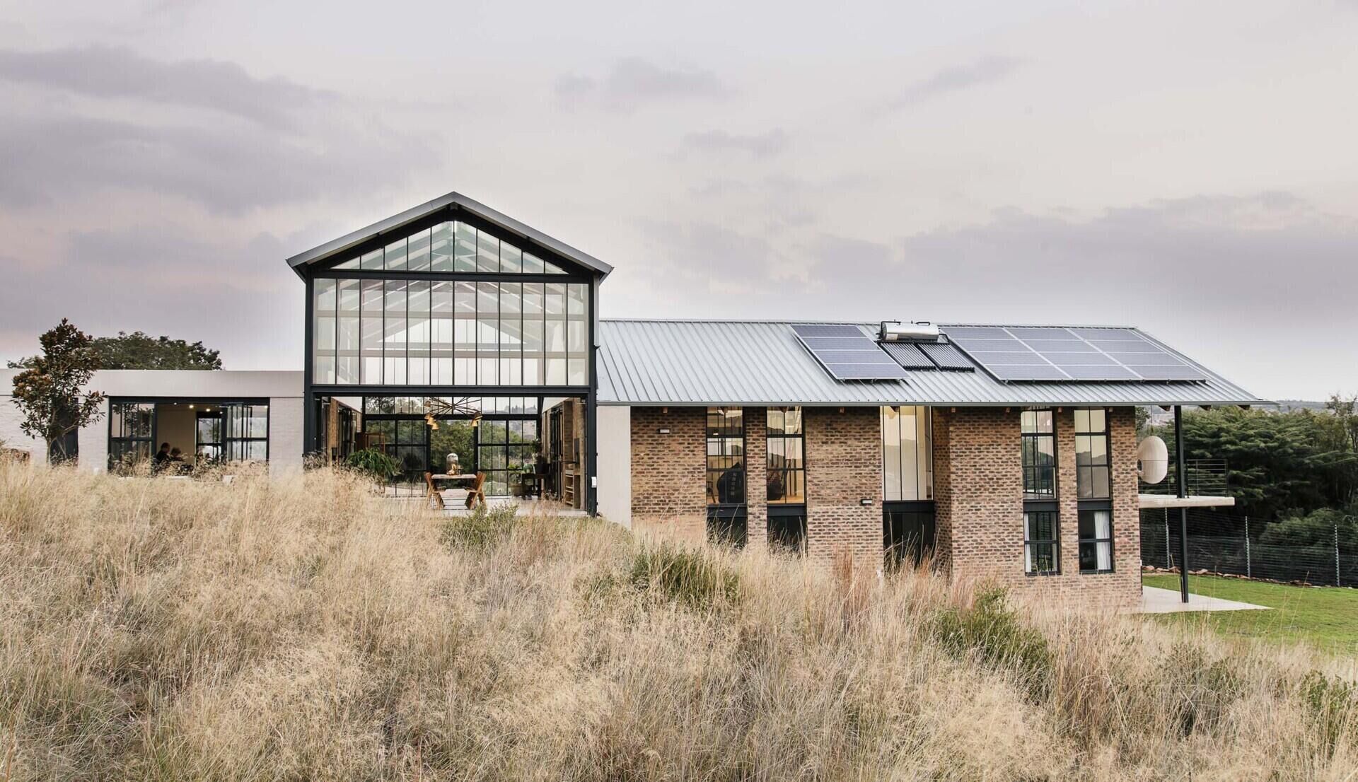 Cement-washed brick, steel, and concrete create a low-maintenance exterior with a strong, modern edge. A double-height conservatory with openable walls and a glass floor becomes the heart of this light-filled home.