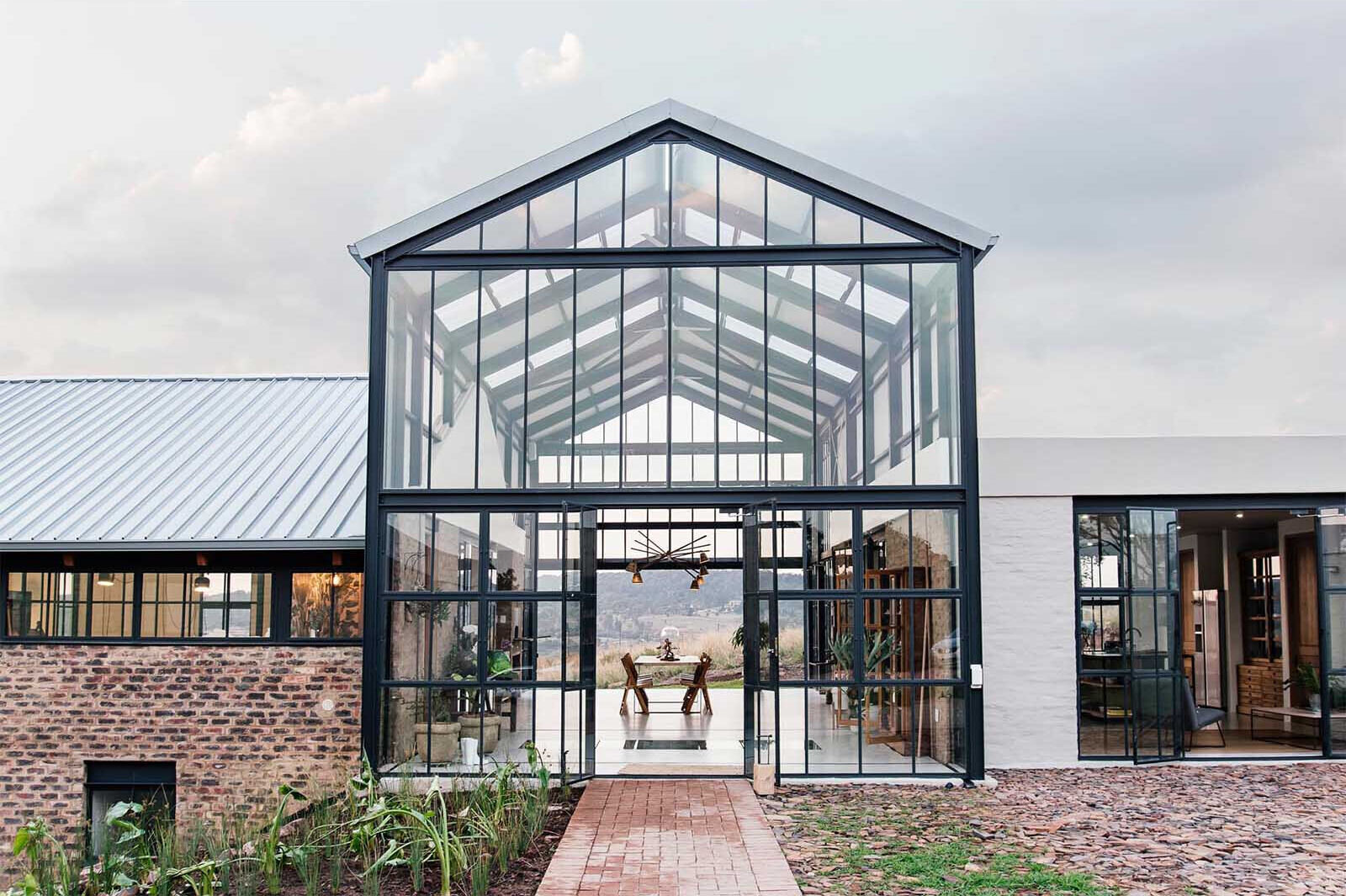 A double-height conservatory with openable walls and a glass floor becomes the heart of this light-filled home.