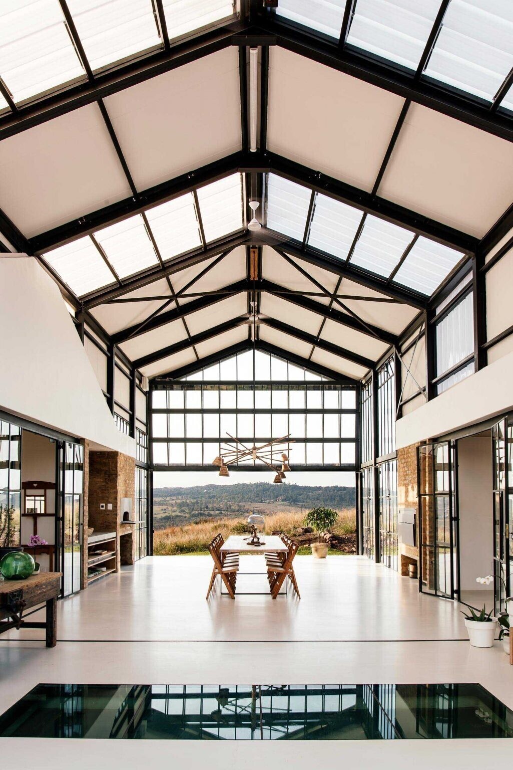 A double-height conservatory with openable walls and a glass floor becomes the heart of this light-filled home.