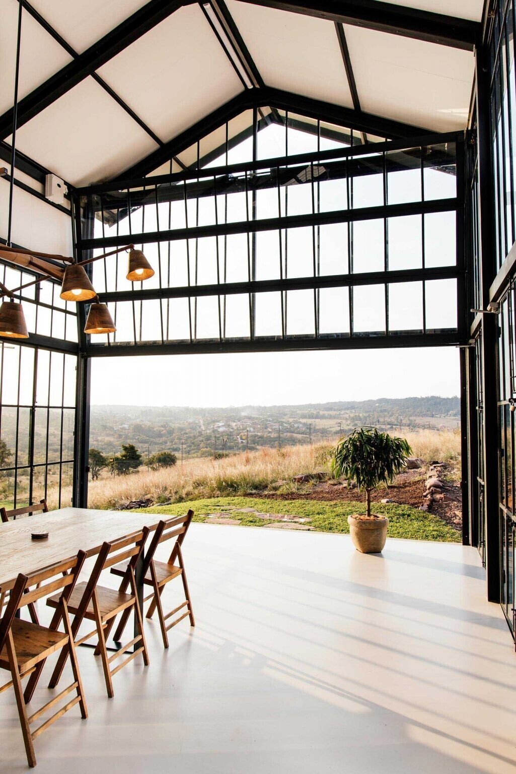 A double-height conservatory with openable walls and a glass floor becomes the heart of this light-filled home.