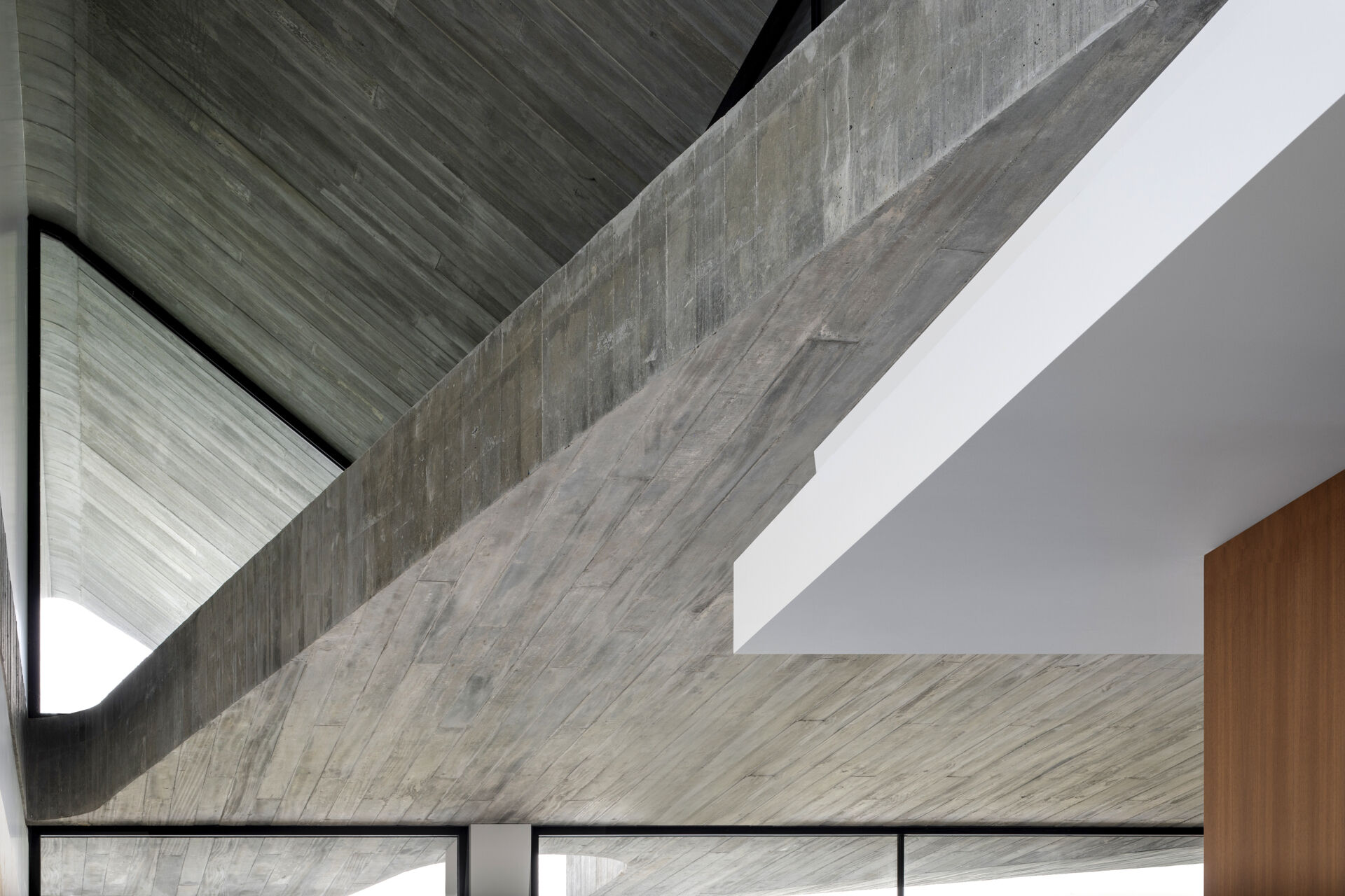 Raw concrete, granite floors, and large openings shape a home filled with natural light and layered textures.