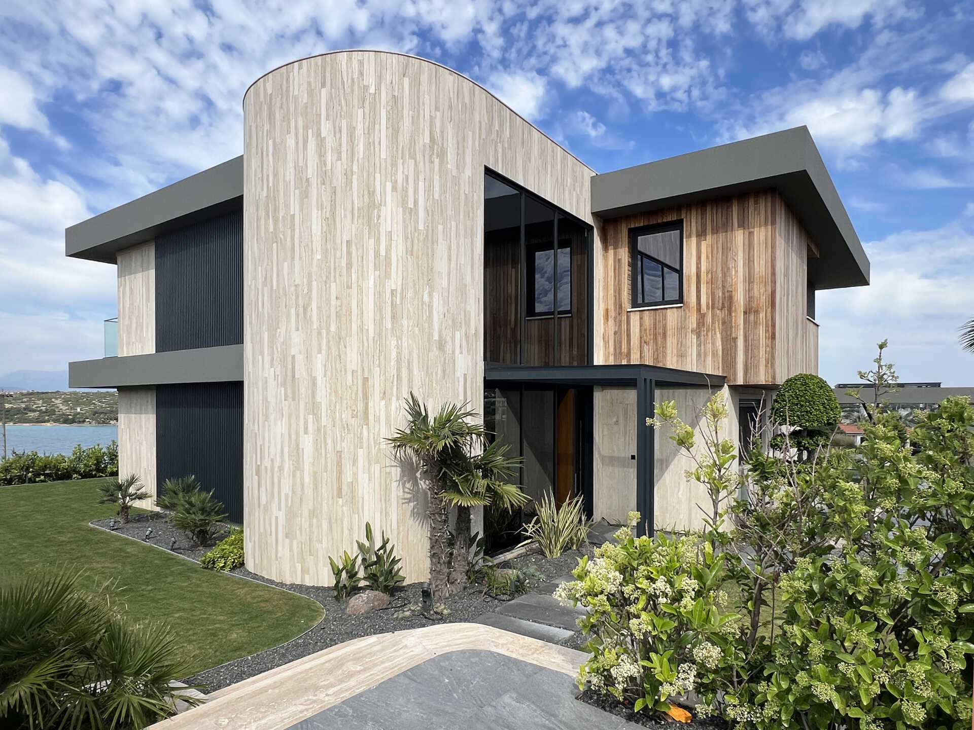 A modern home has wave-inspired architecture with sculptural eaves that create shaded outdoor spaces throughout the day.