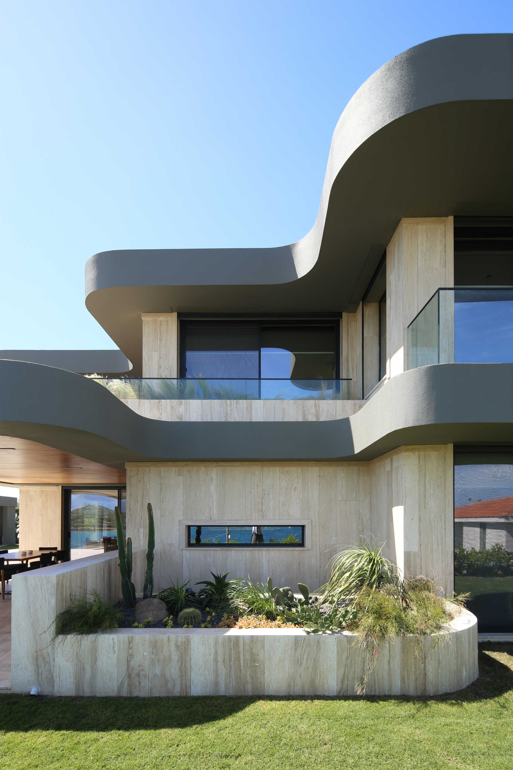 A modern home has wave-inspired architecture with sculptural eaves that create shaded outdoor spaces throughout the day.
