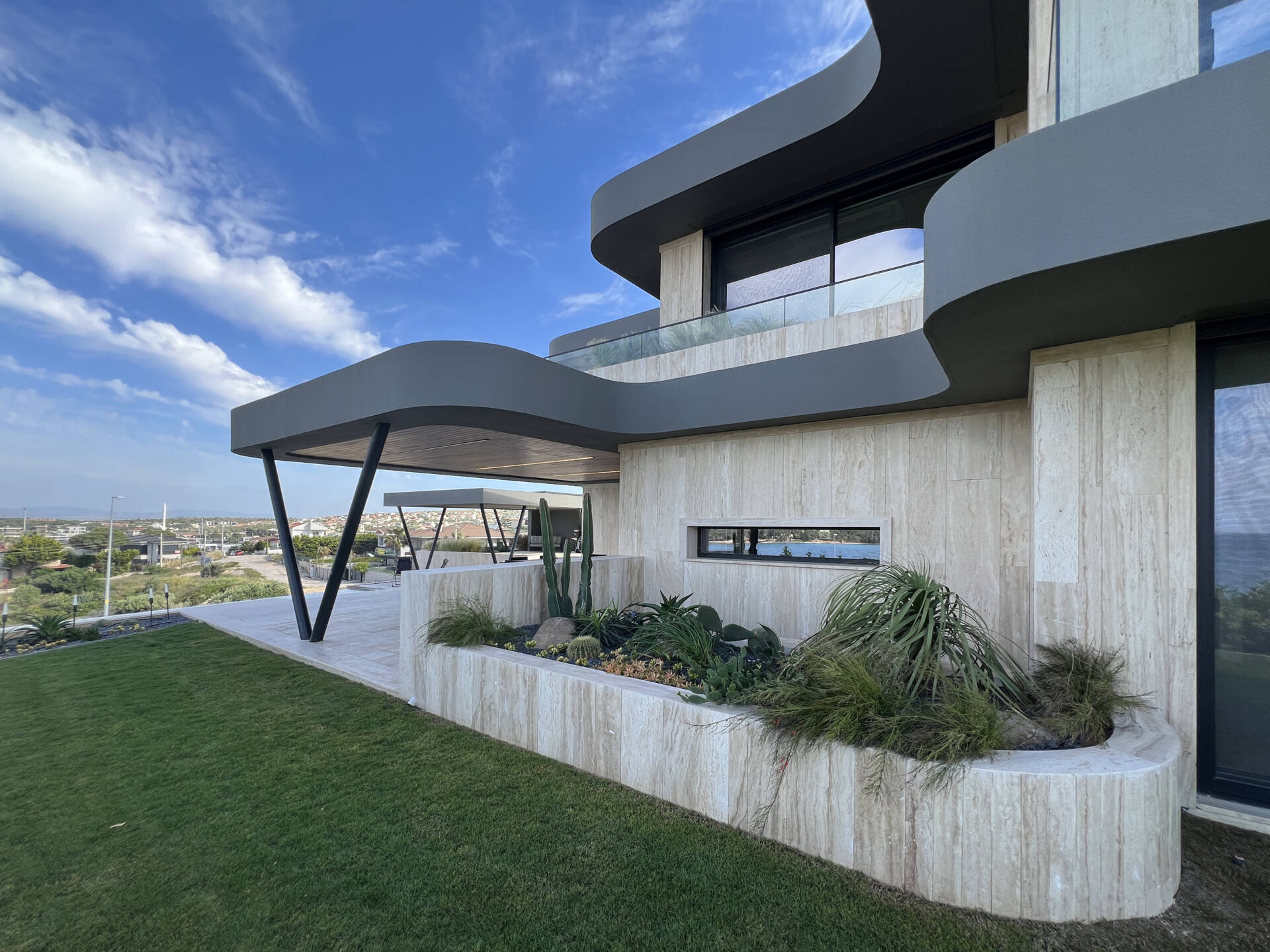 A modern home has wave-inspired architecture with sculptural eaves that create shaded outdoor spaces throughout the day.