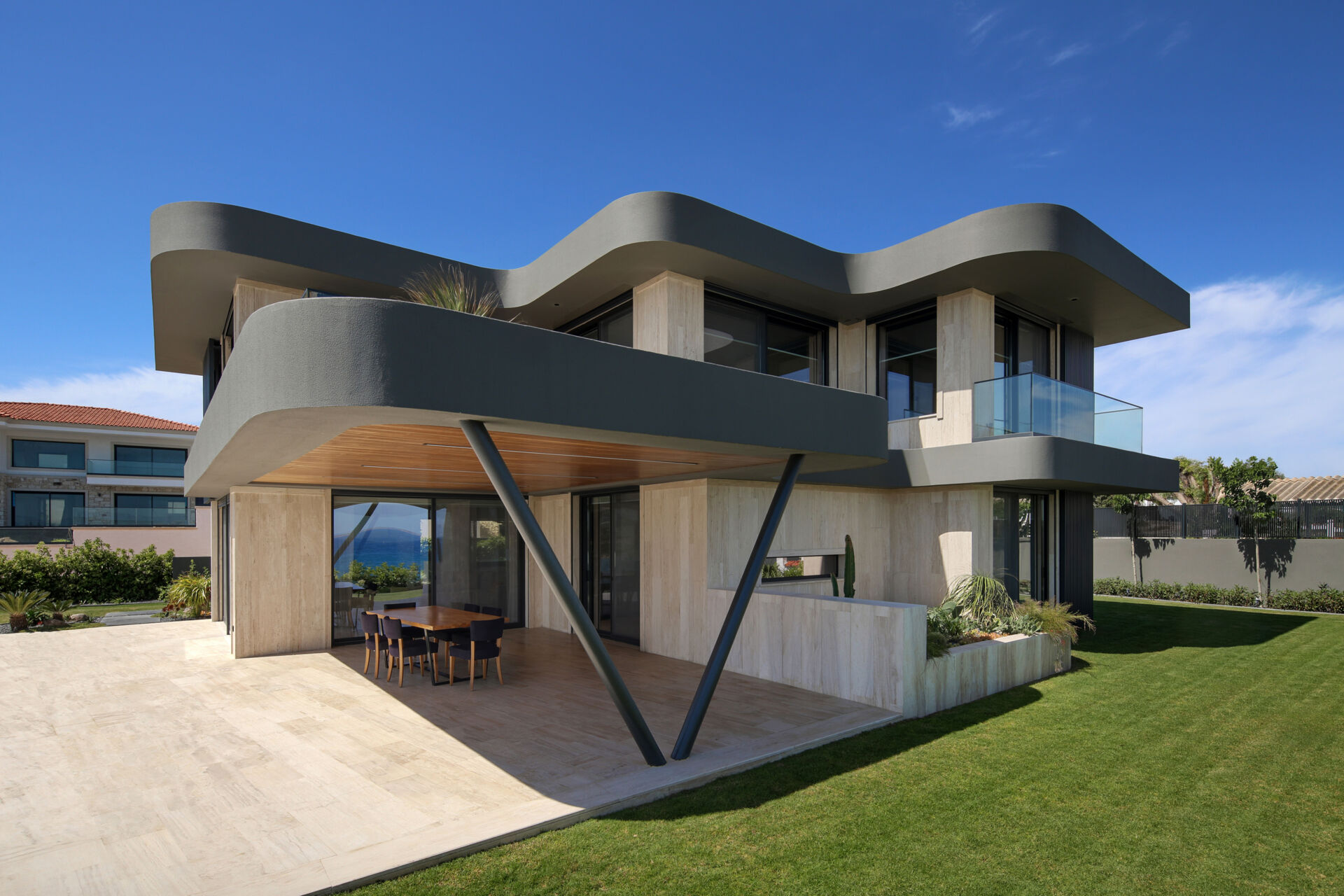 A modern home has wave-inspired architecture with sculptural eaves that create shaded outdoor spaces throughout the day.