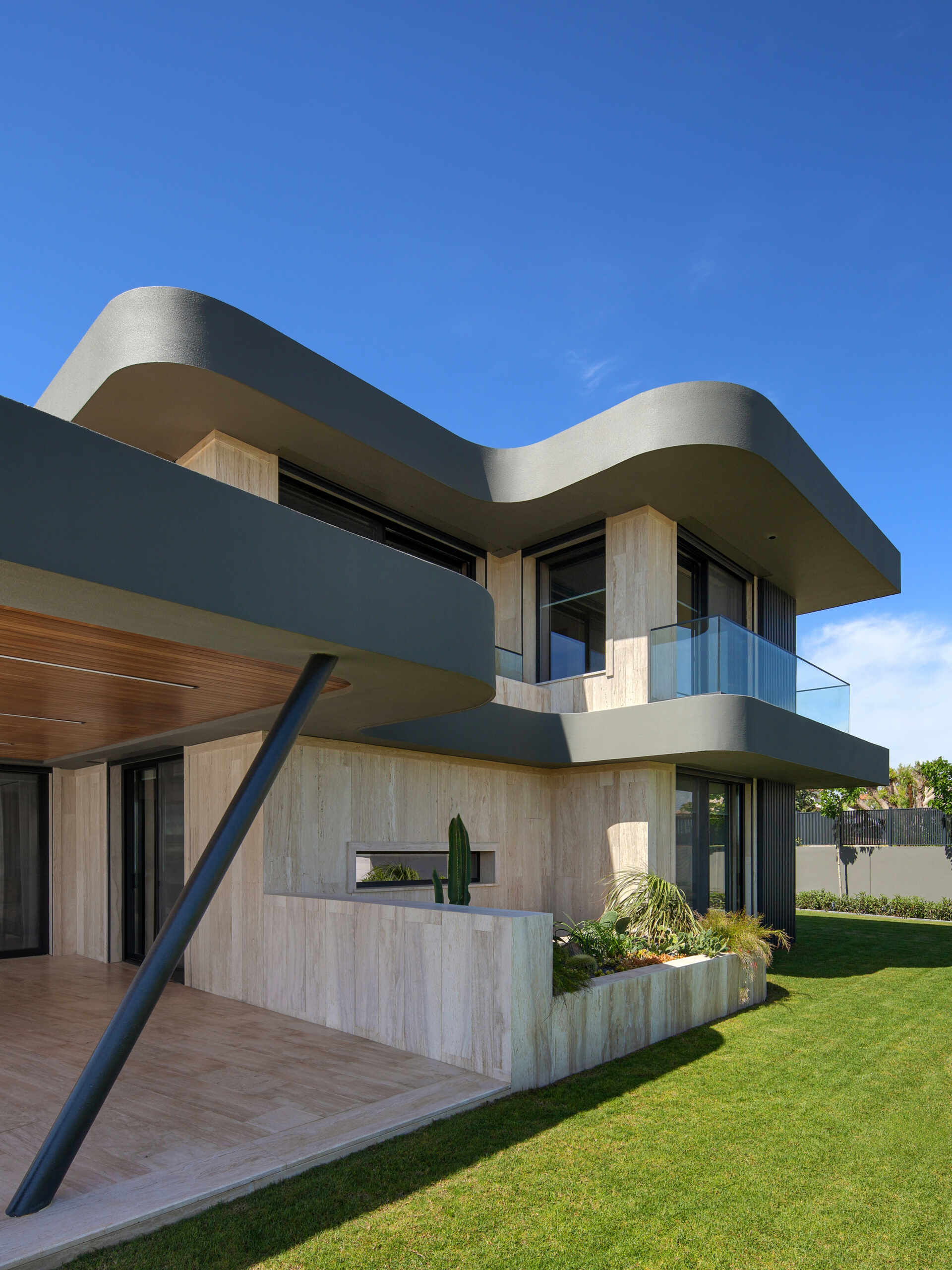 A modern home has wave-inspired architecture with sculptural eaves that create shaded outdoor spaces throughout the day.