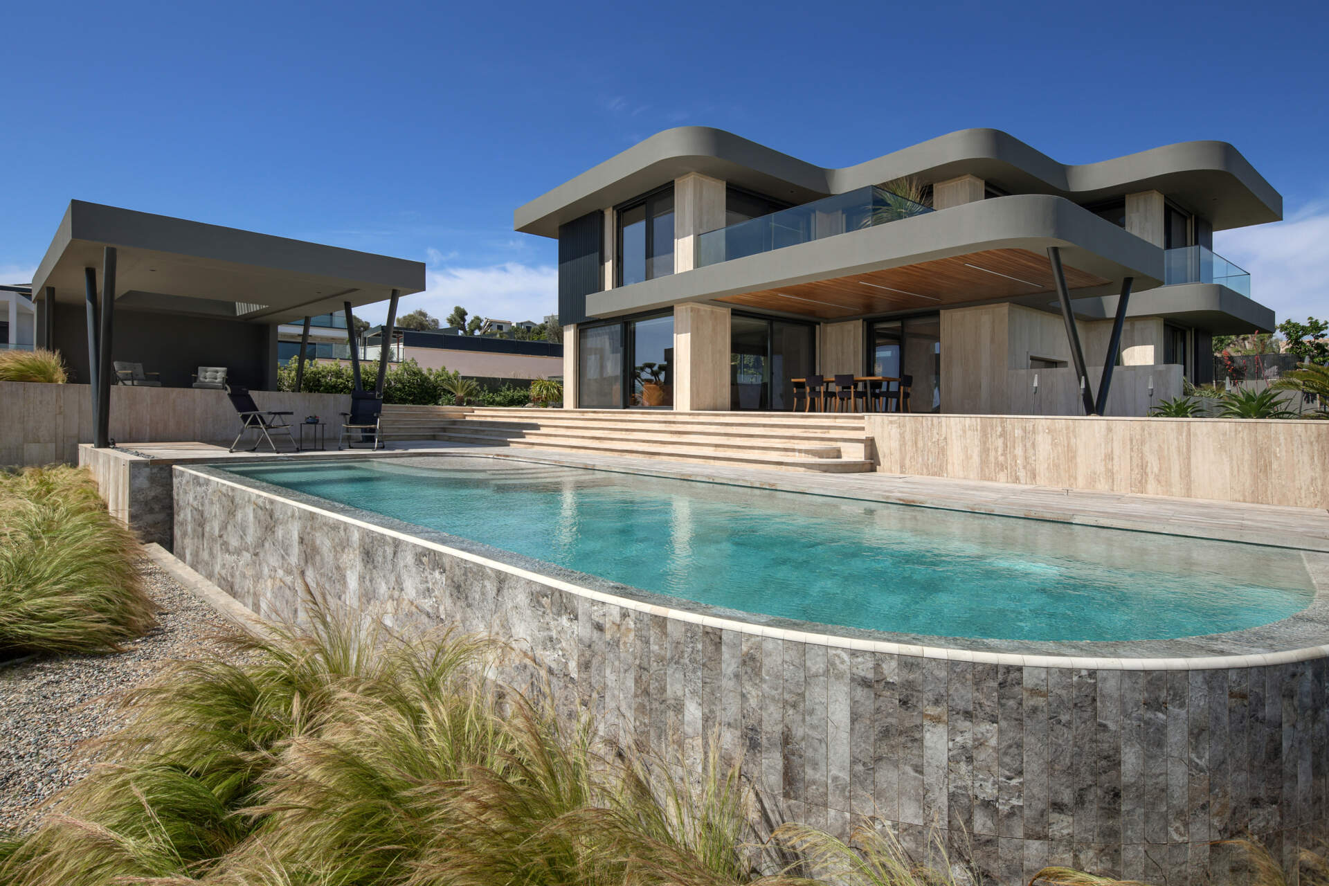 A seamless indoor-outdoor layout where living spaces open directly to the pool, garden, and expansive coastal views.