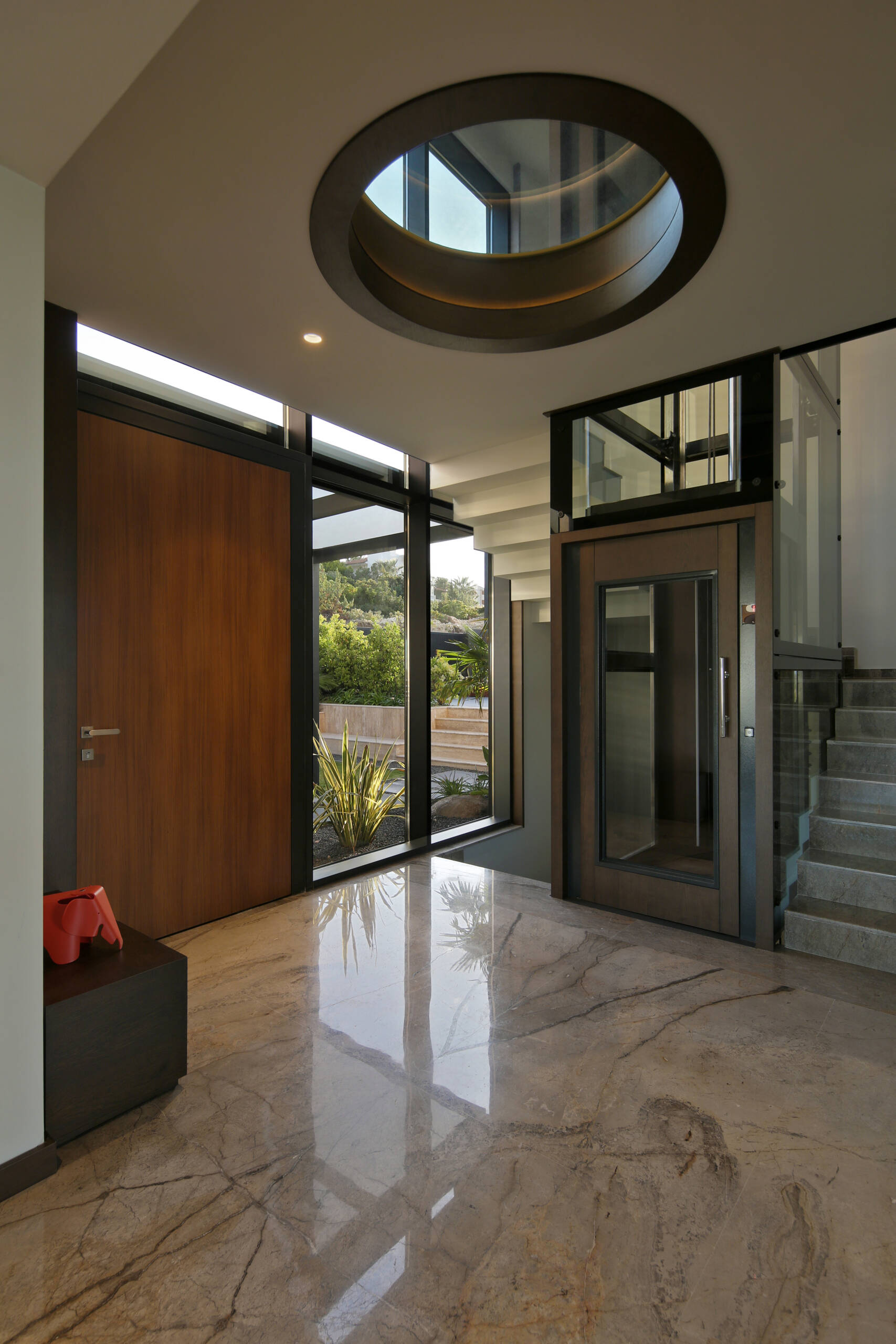 A unique entry sequence through a sunken garden filled with lemon and palm trees, leading into a calm, modern interior.