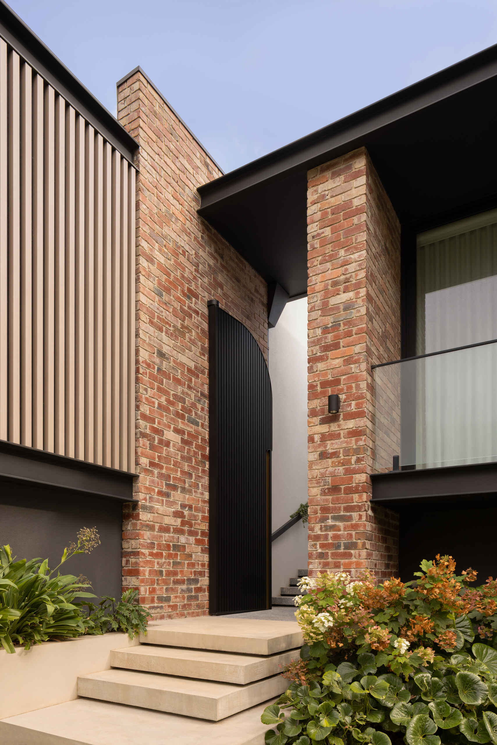The journey begins with steps that lead to a large metal courtyard door. Passing through it introduces a slower pace, where movement becomes intentional and the transition into the home feels defined and memorable. The use of reclaimed clinker bricks ties the home back to its past, while also grounding it within the established character of the area.