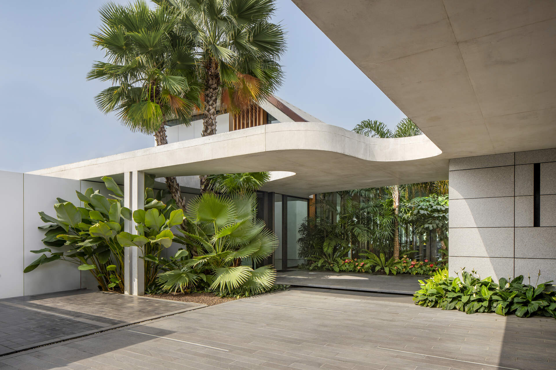 A striking concrete canopy leads into a landscaped forecourt, creating a calm and open arrival sequence.