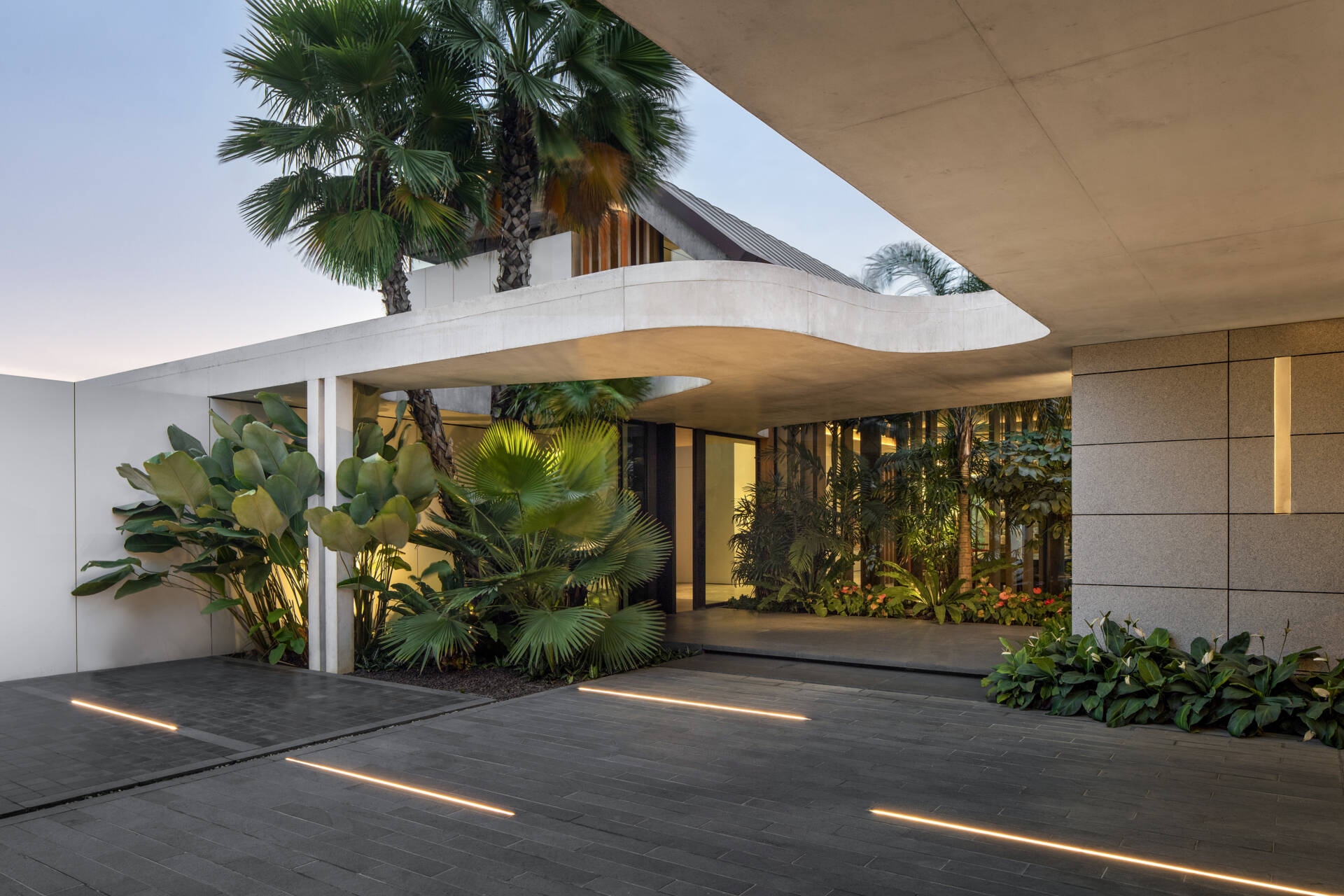 A striking concrete canopy leads into a landscaped forecourt, creating a calm and open arrival sequence.