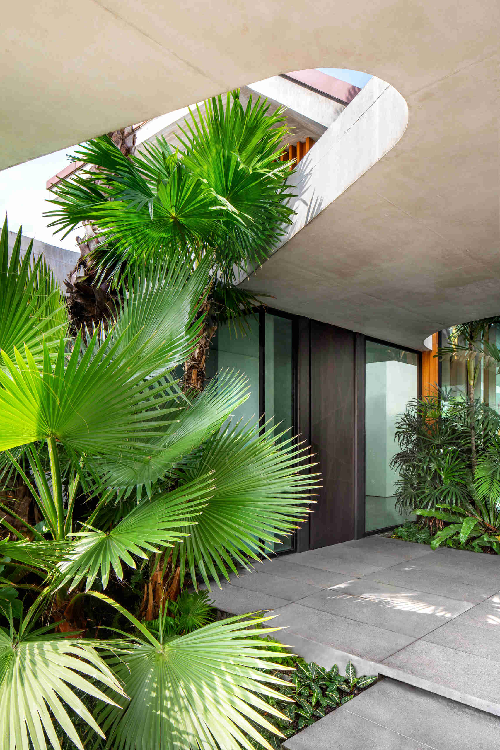 A striking concrete canopy leads into a landscaped forecourt, creating a calm and open arrival sequence.