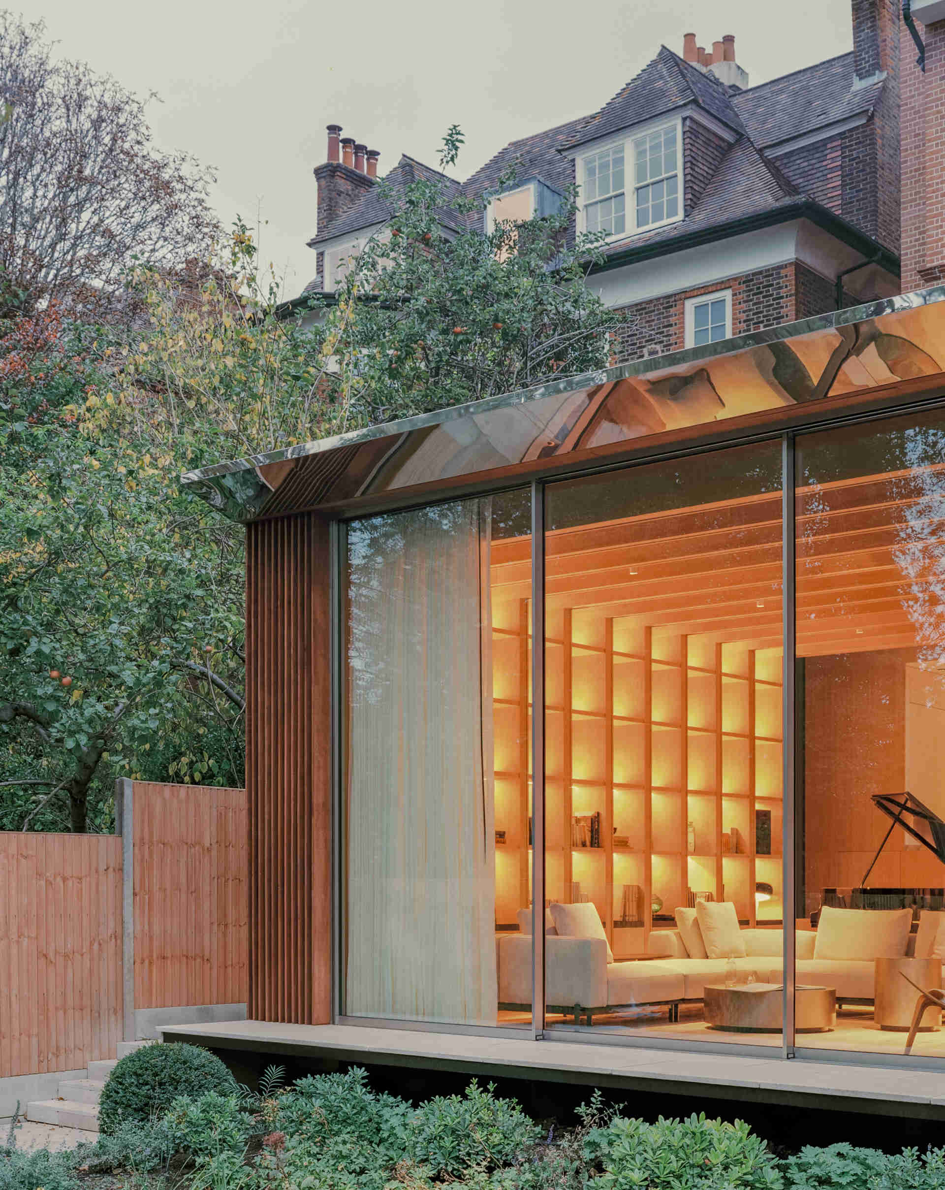 This cascading extension wrapped in iroko timber and topped with a reflective roof blends structure and greenery in a striking way.