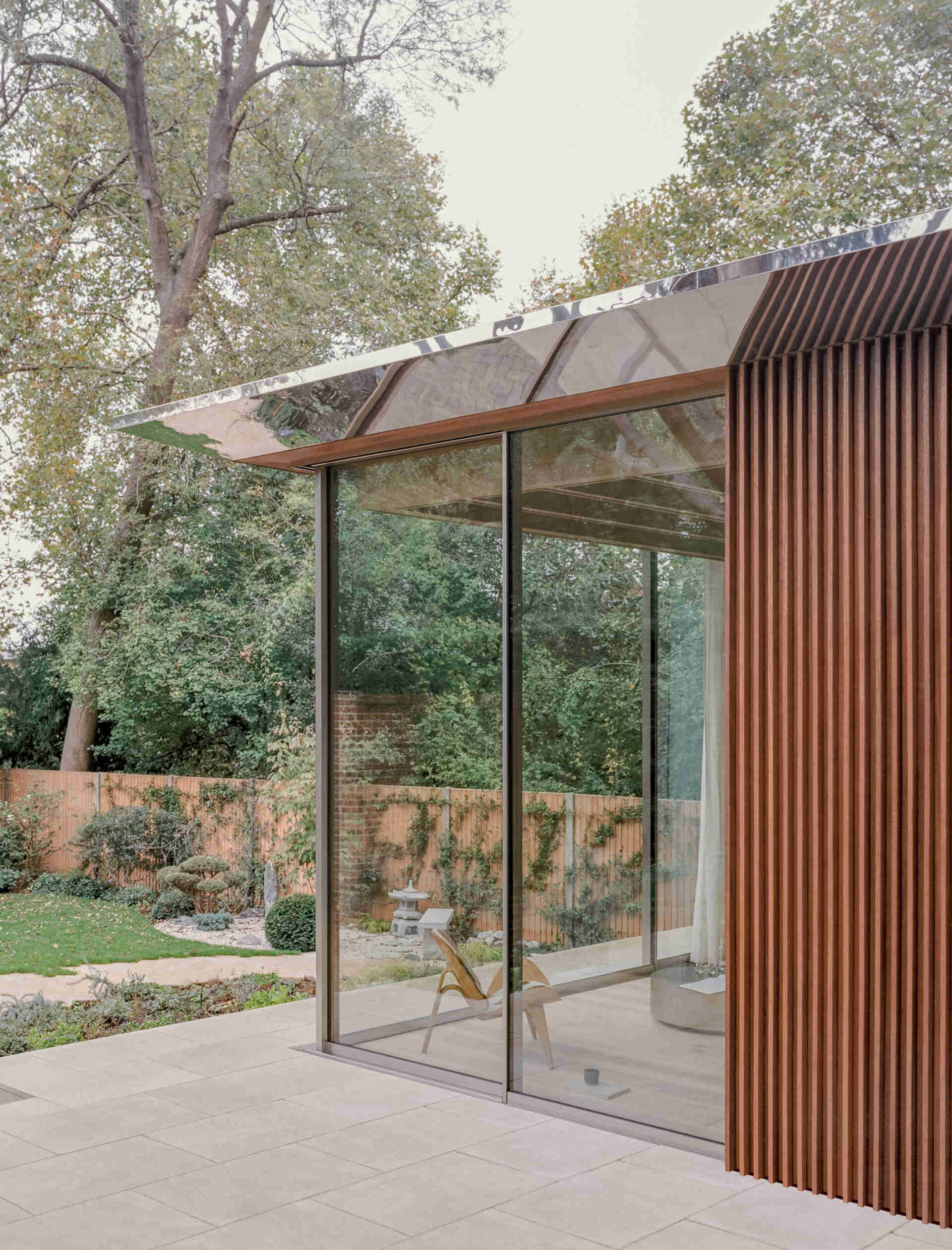 This cascading extension wrapped in iroko timber and topped with a reflective roof blends structure and greenery in a striking way.