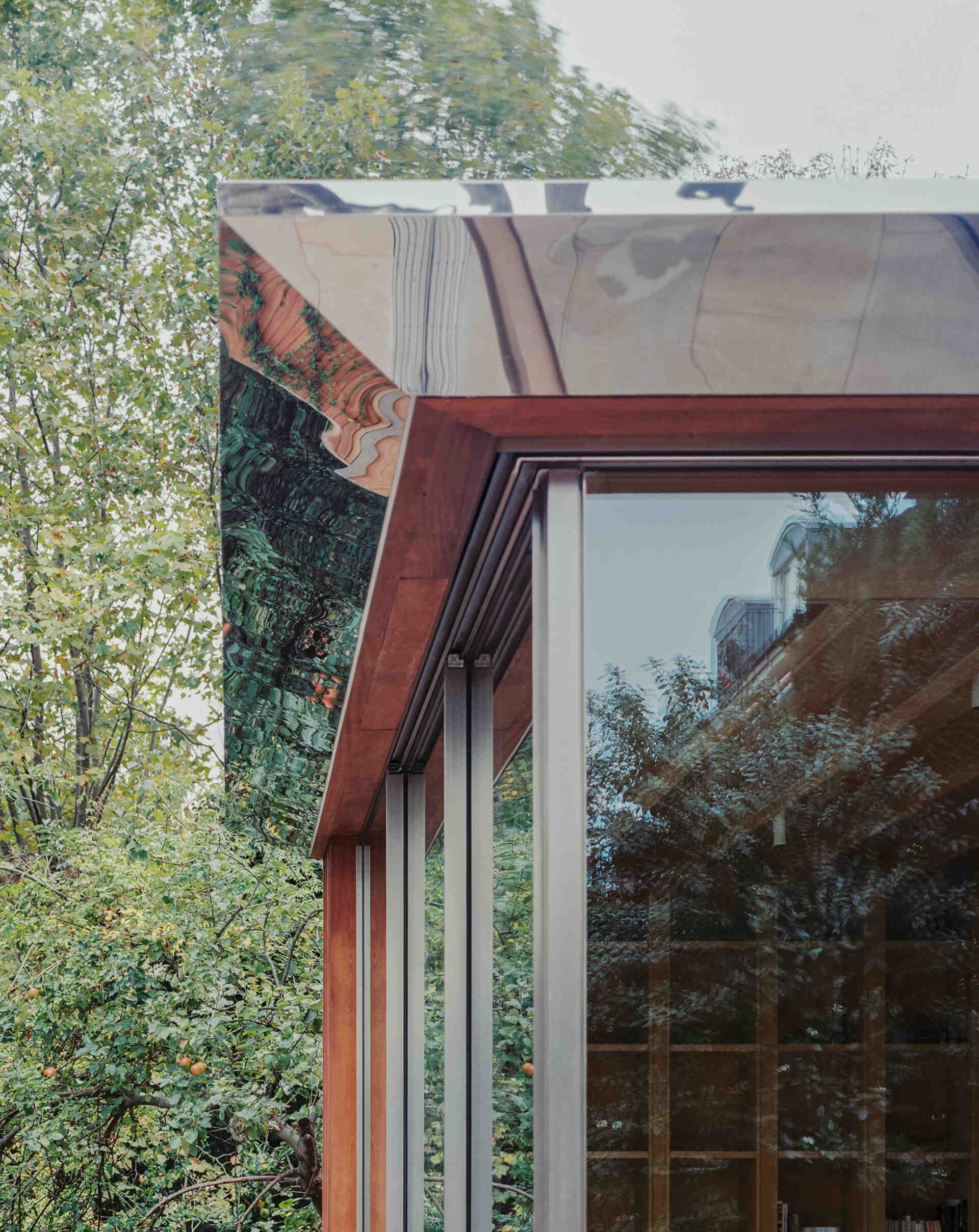 This cascading extension wrapped in iroko timber and topped with a reflective roof blends structure and greenery in a striking way.