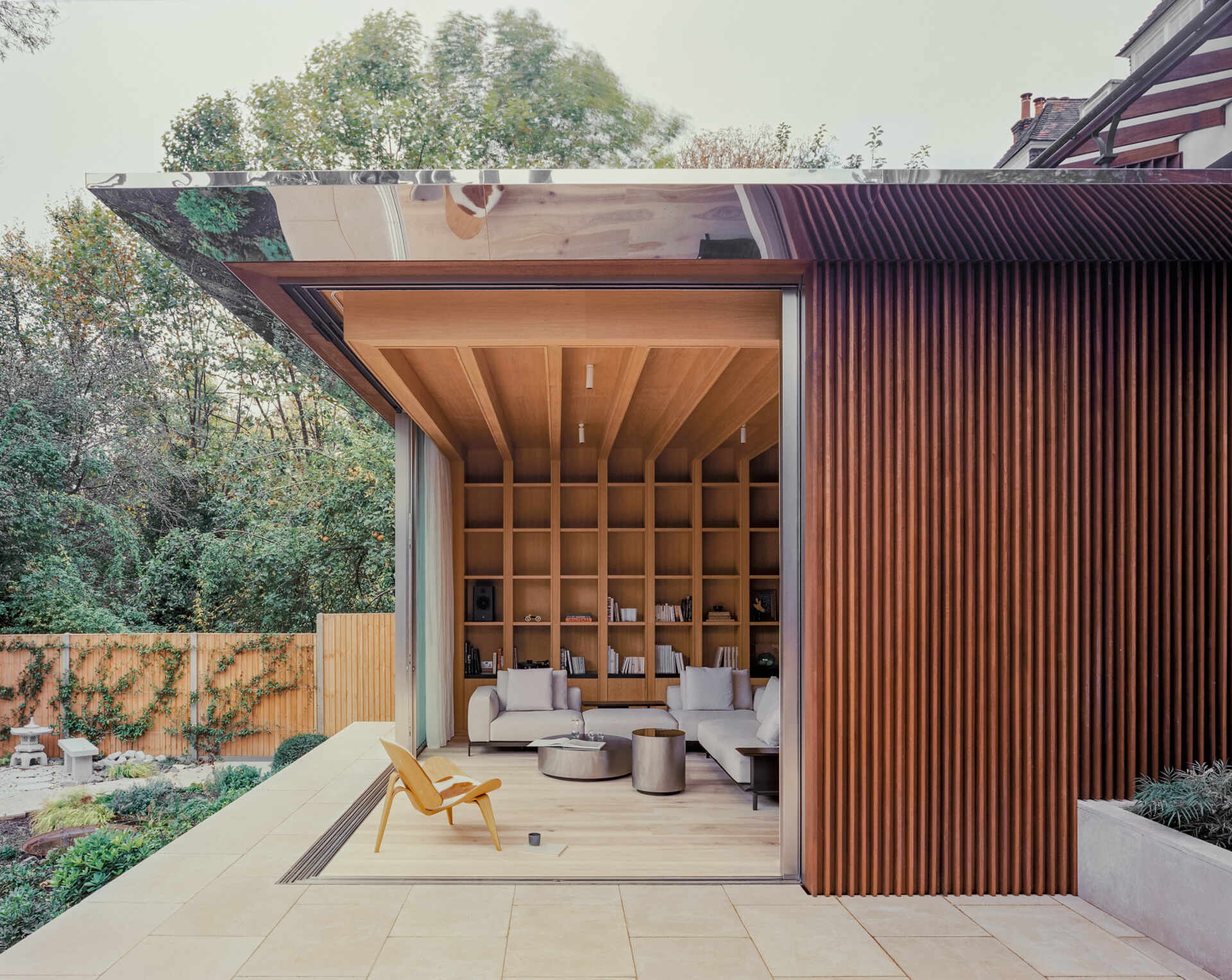 A seamless glass corner opens fully to the garden, creating uninterrupted views and a strong indoor-outdoor connection.