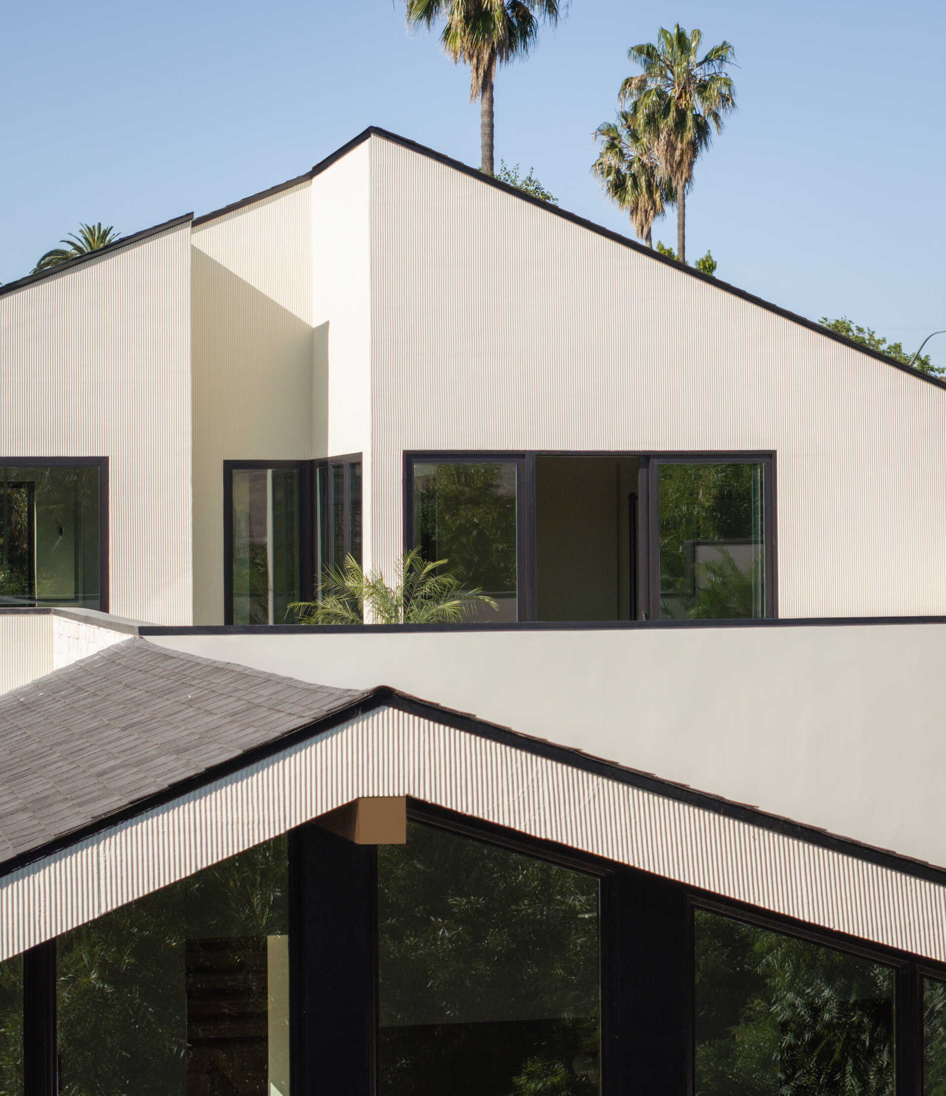 A modern home exterior in stucco and limestone uses texture and light to create depth on a narrow sloped lot.