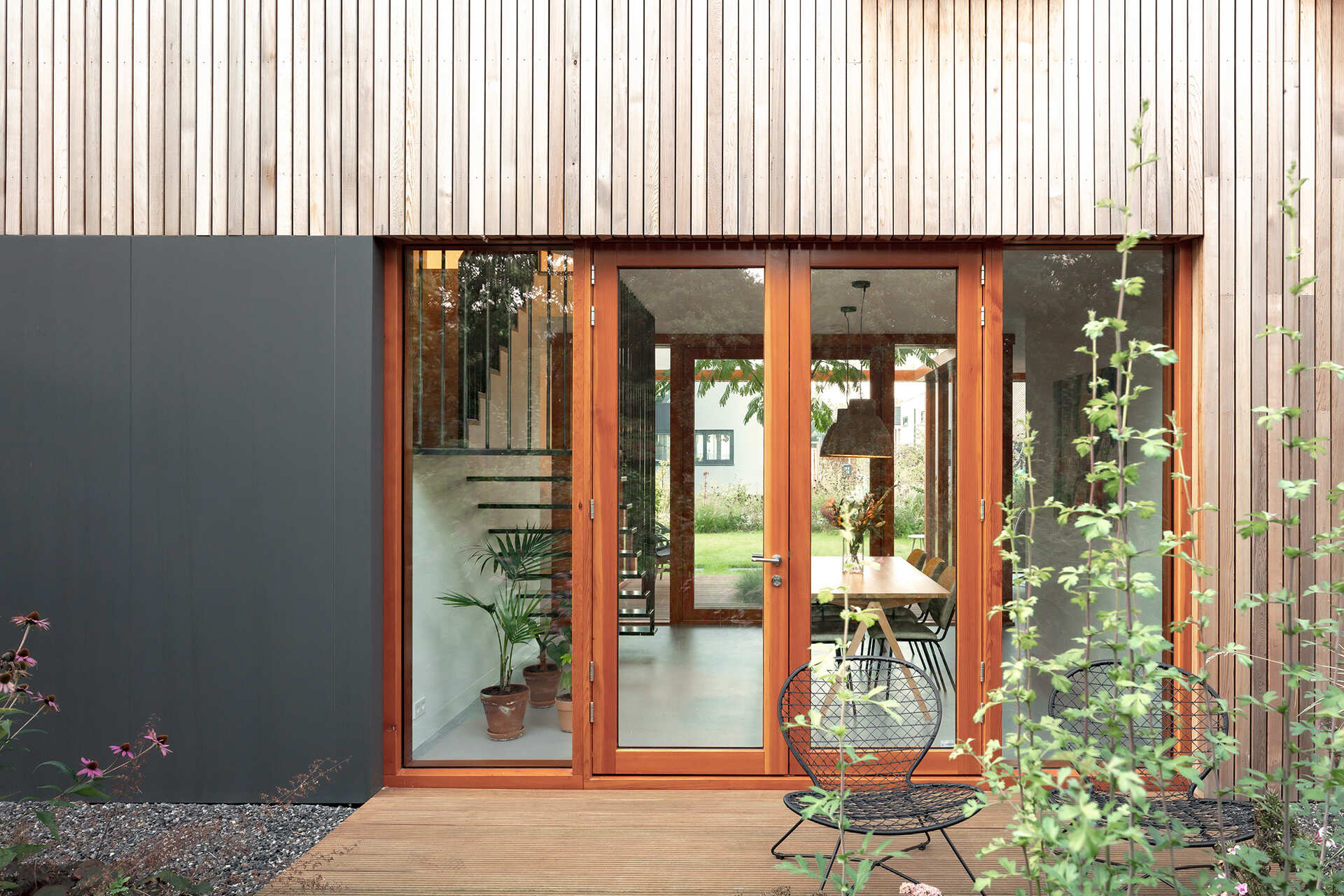 This Rotterdam home features a sculptural shape with wood siding, softened by surrounding gardens and selective openings.