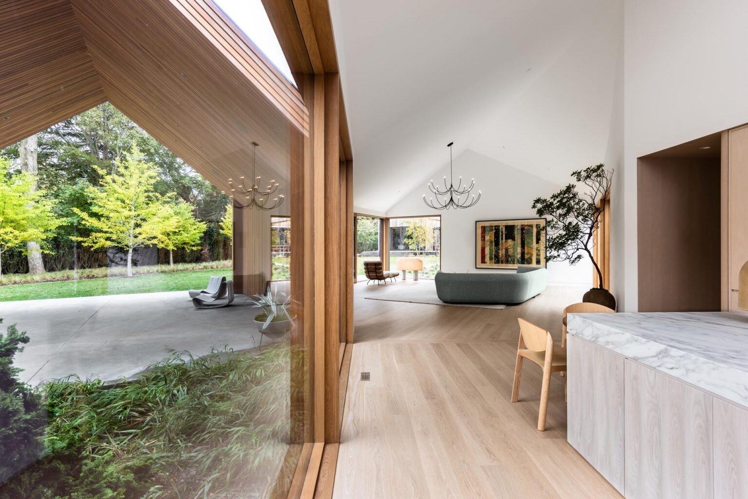 A bright white interior with angled ceilings reflects the home’s sculptural roofline, creating an open and airy atmosphere.