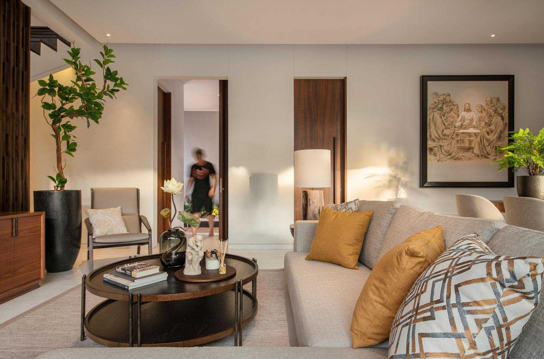 The living room is anchored by artistic panels that partially conceal the staircase behind them. These panels double as a backdrop for the television, turning a functional feature into a design focal point.