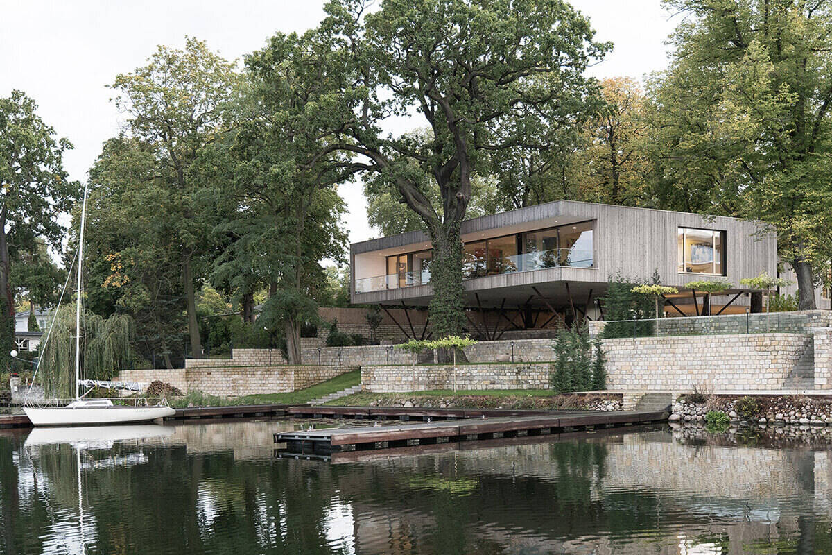 A modern home in Potsdam designed on posts to protect the landscape while creating a striking elevated form above the riverfront.